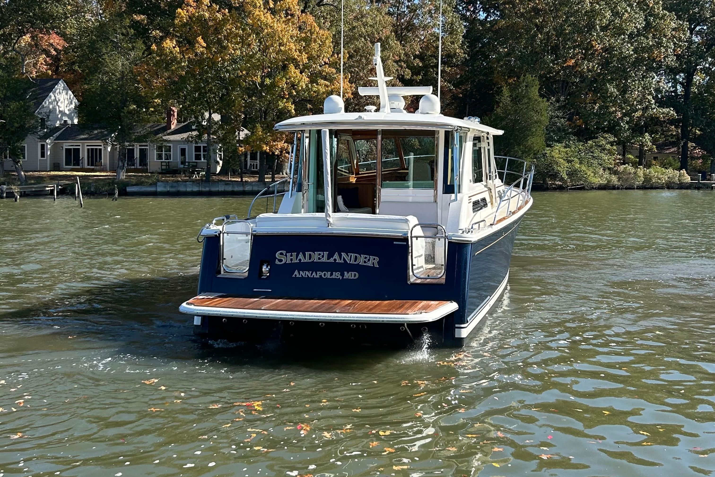 2022 Sabre 45 Salon Express boat on water near shoreline with trees.