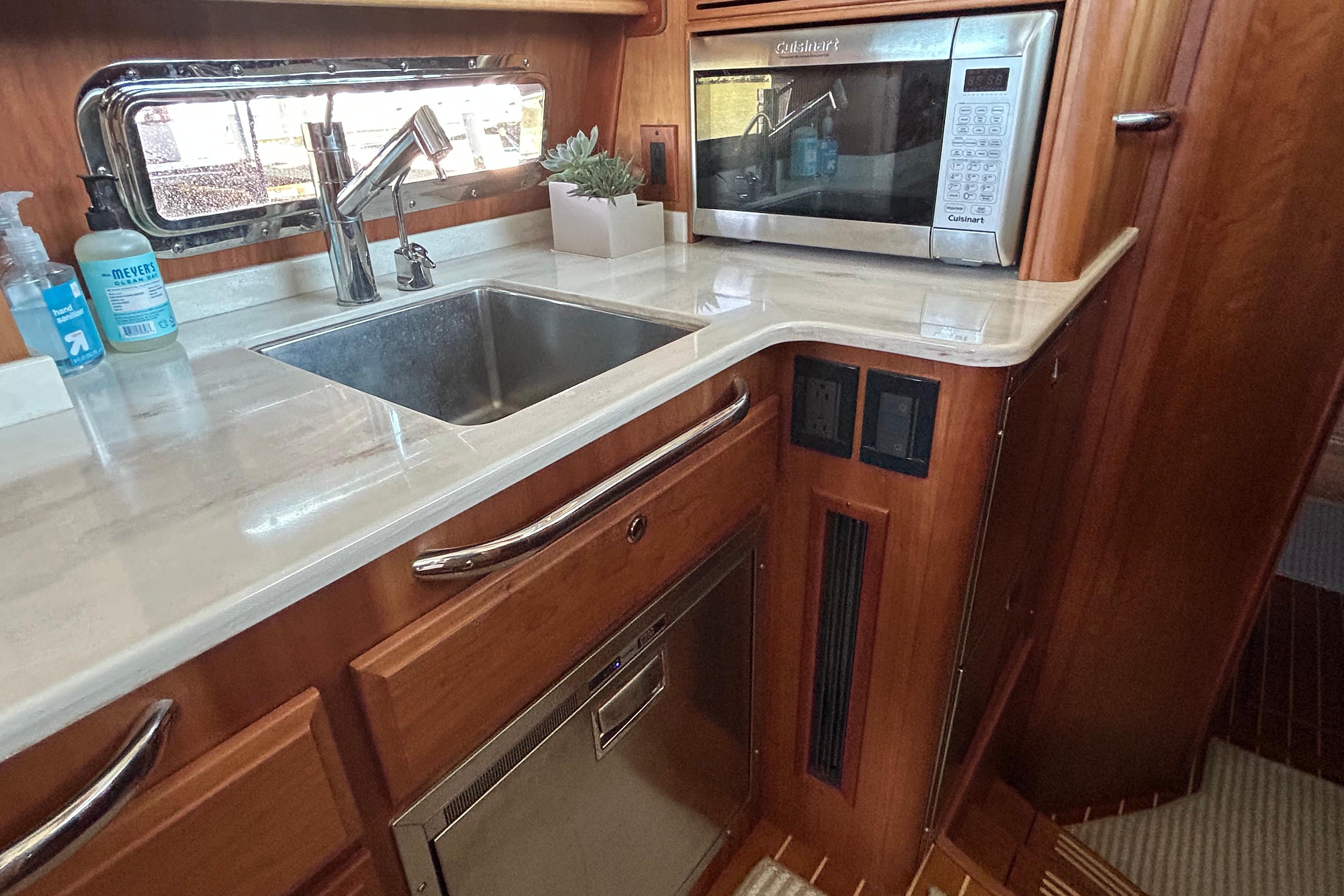 Modern kitchen area in 2022 Sabre 45 Salon Express yacht with sink and microwave.