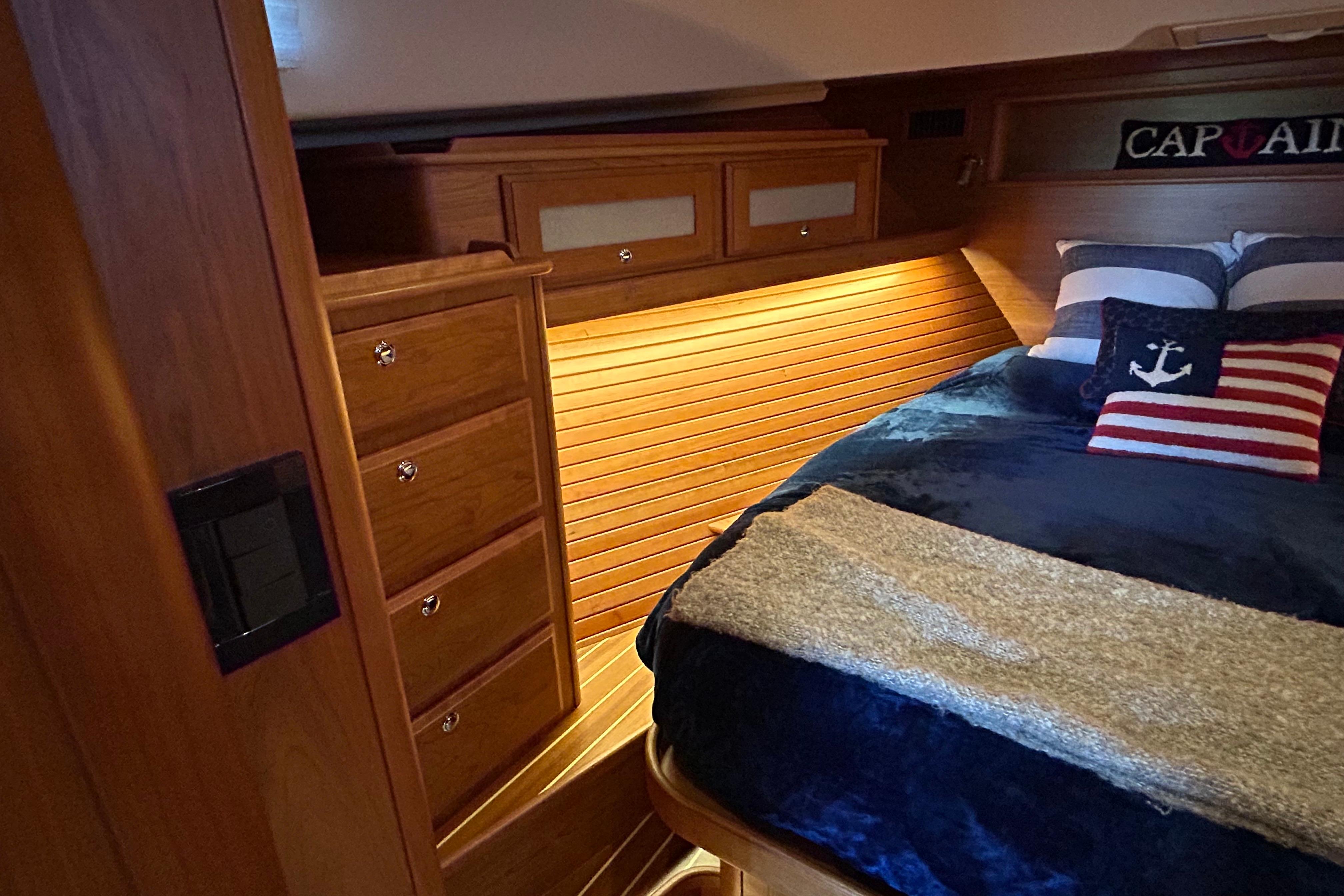 Interior of 2022 Sabre 45 Salon Express with cozy wooden cabinetry and nautical-themed bedding.