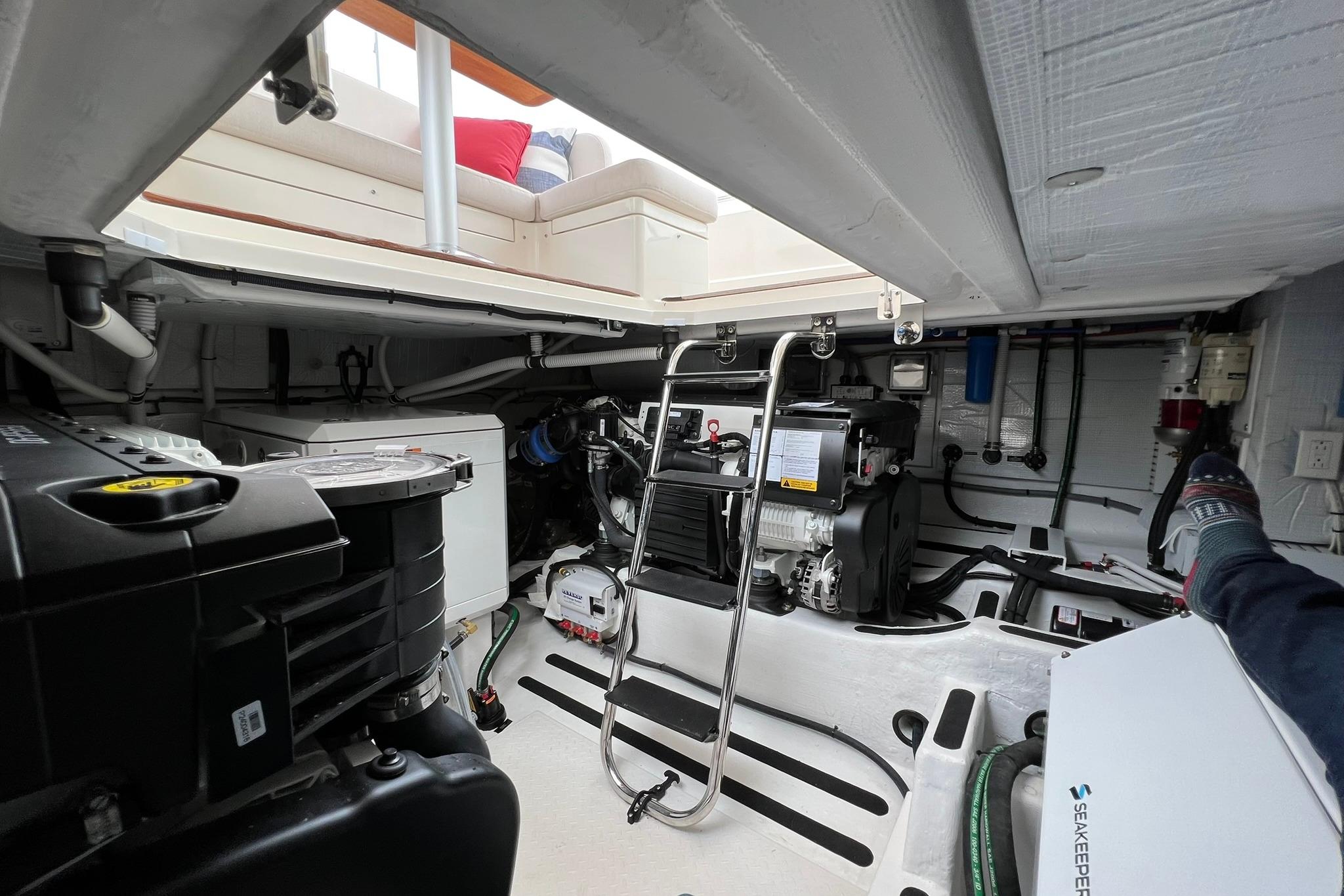 Engine room of 2022 Sabre 45 Salon Express yacht, showcasing mechanical components and seating area.