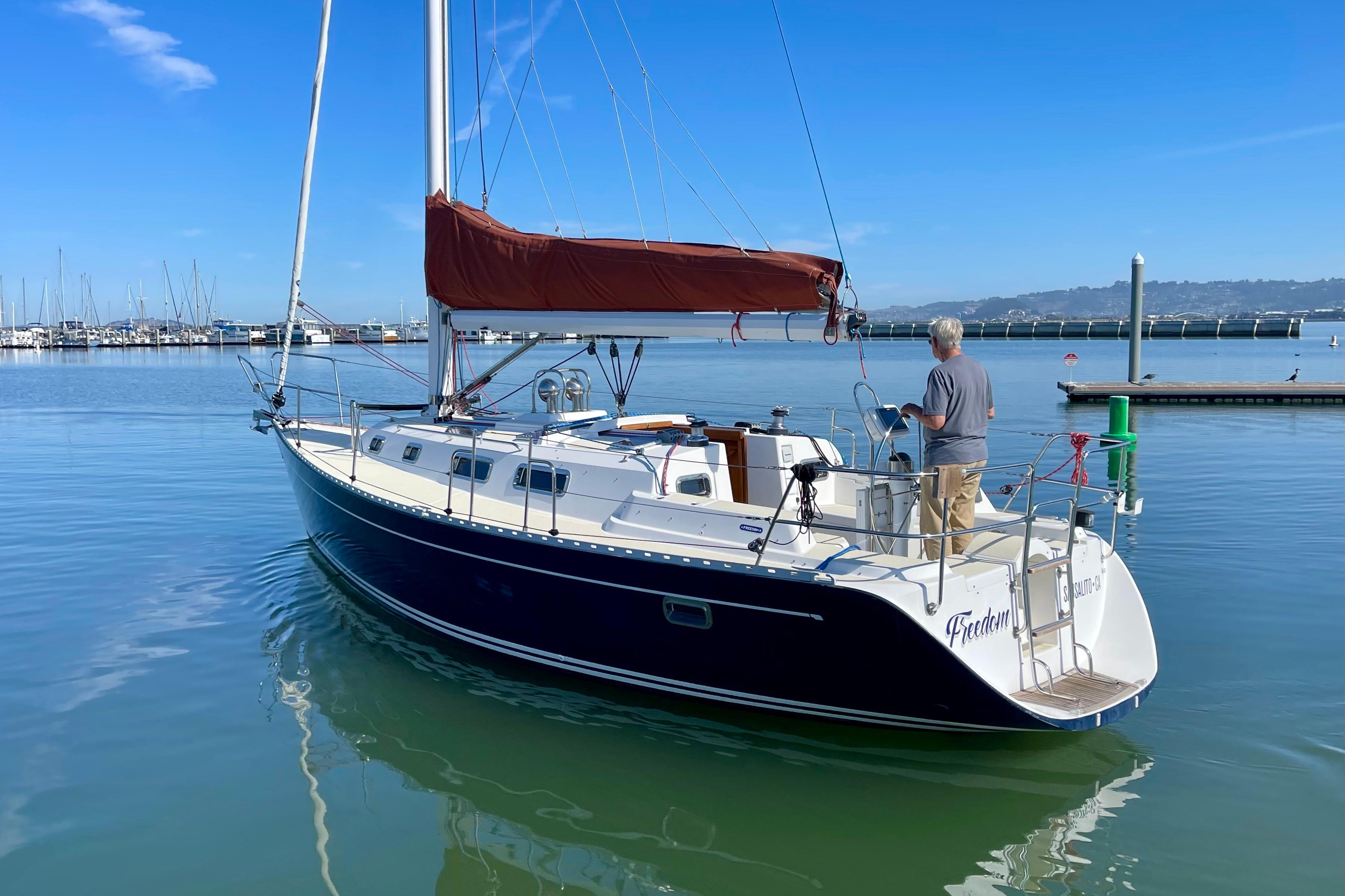 Sailboat Freedom 35, 1995 model, docked in calm marina waters under clear blue sky.