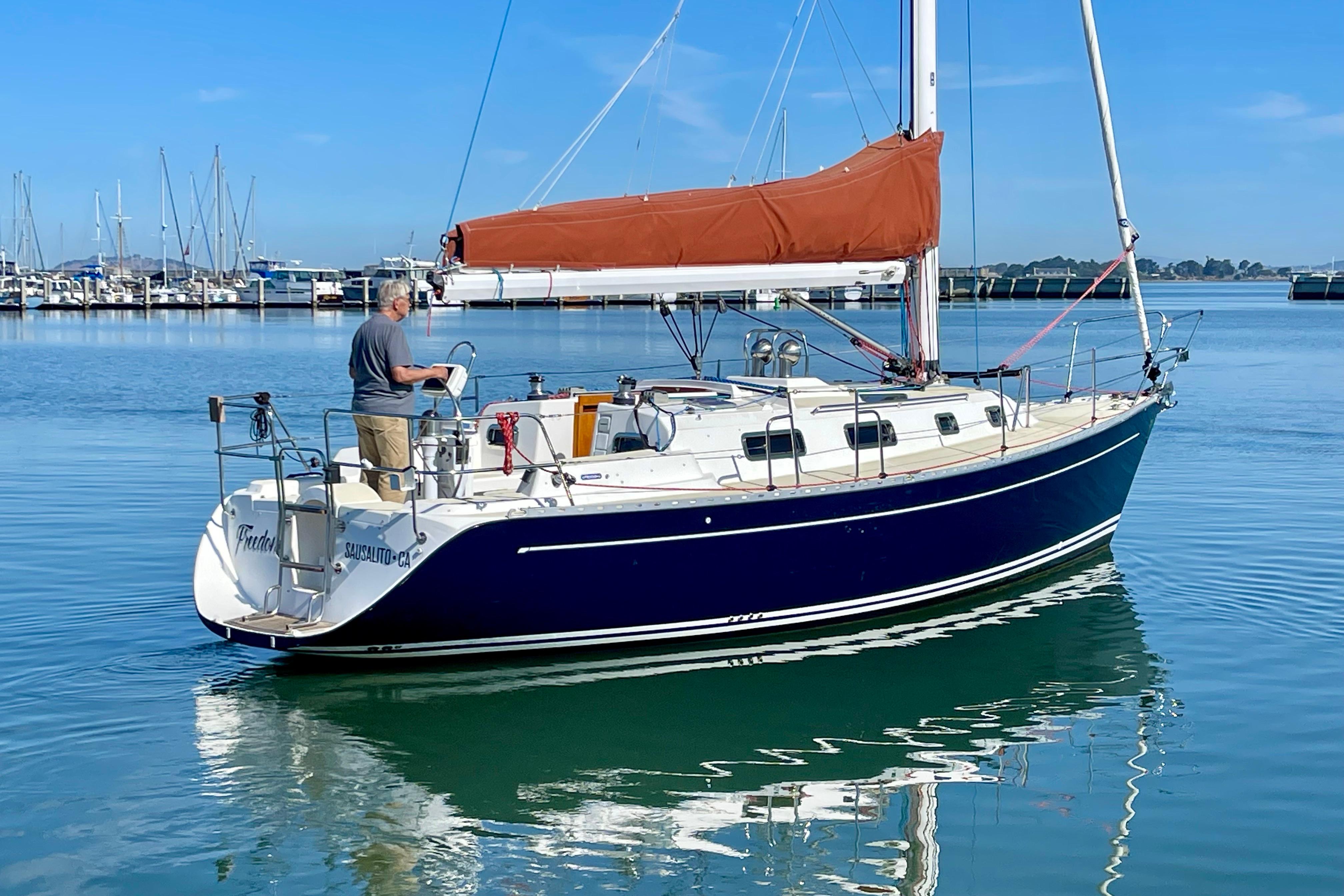 Sailboat Freedom 35, 1995 model, docked in calm marina waters under clear blue sky.