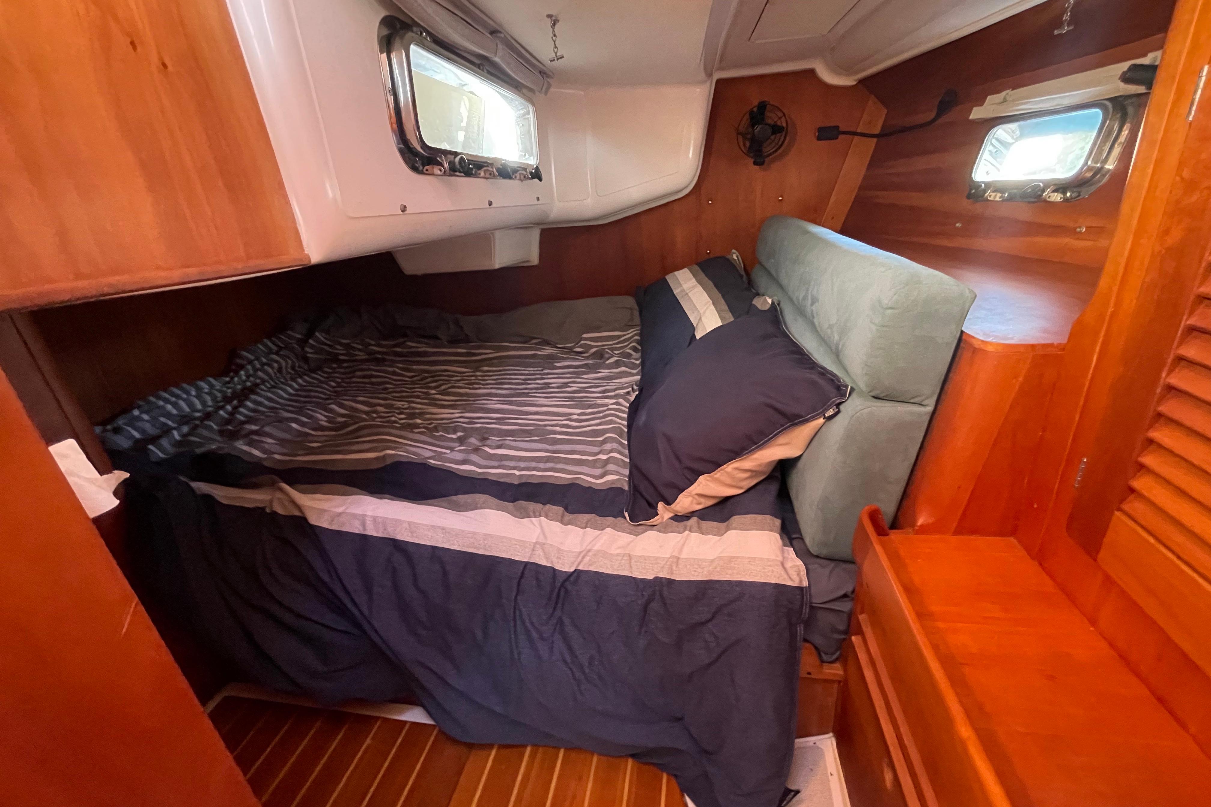 Cozy cabin interior of 1995 Freedom 35 sailboat with striped bedding and wooden accents.