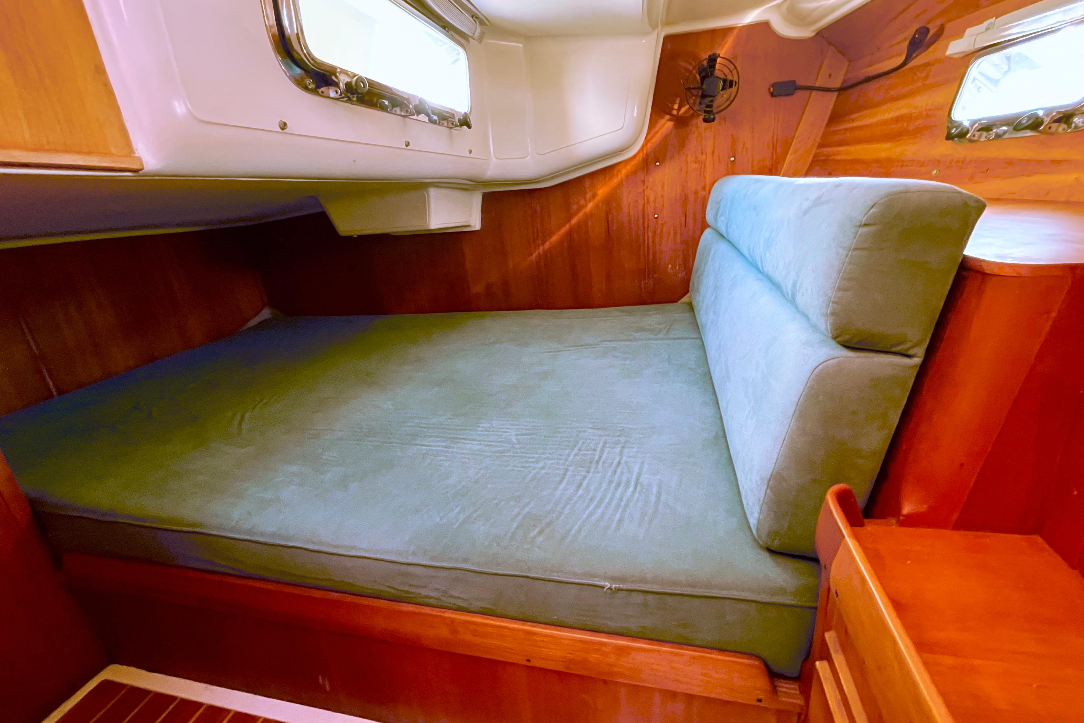 Cozy cabin interior of 1995 Freedom 35 sailboat with cushioned seating and wooden accents.
