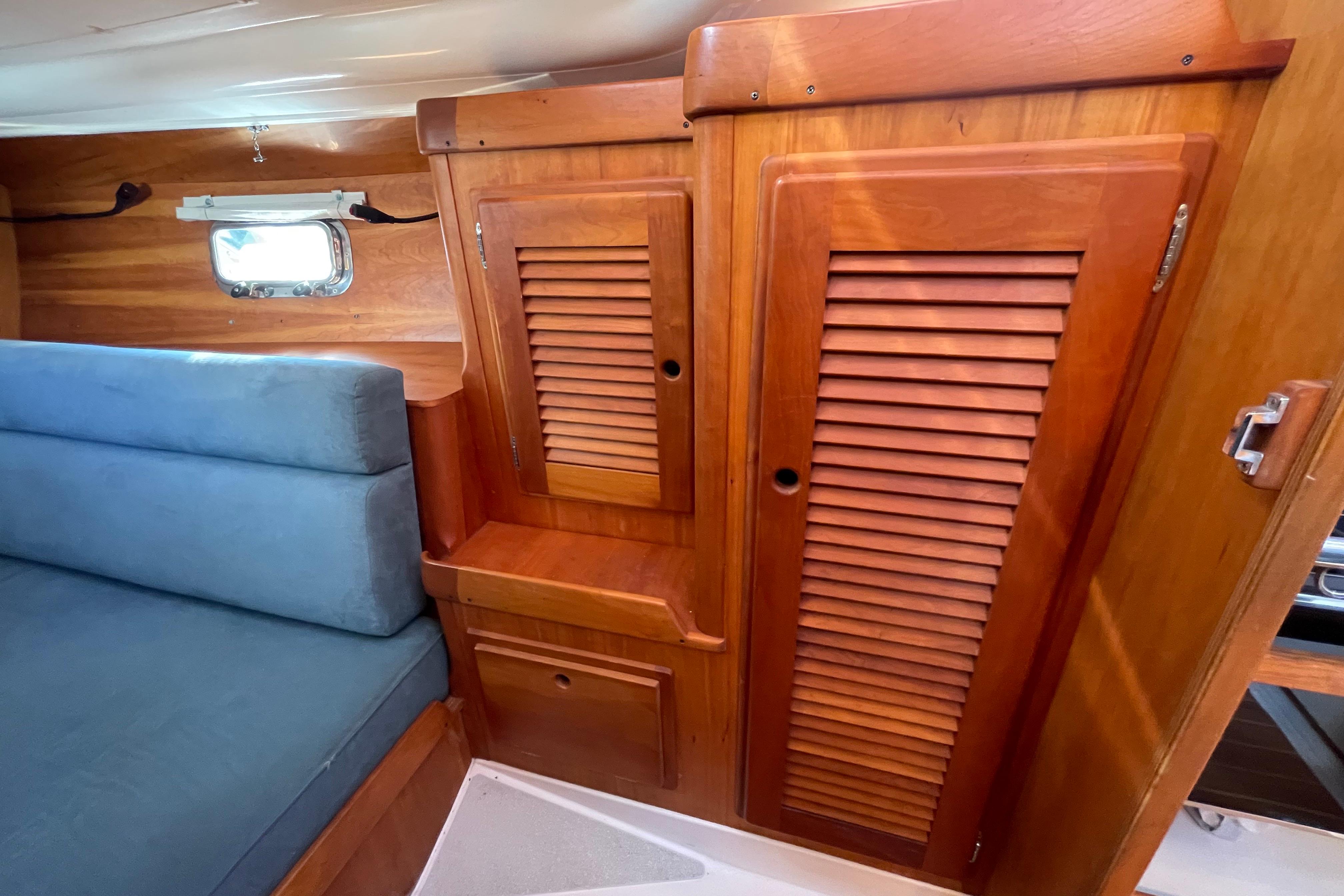 Cozy interior of 1995 Freedom 35 sailboat with wooden cabinets and blue seating.