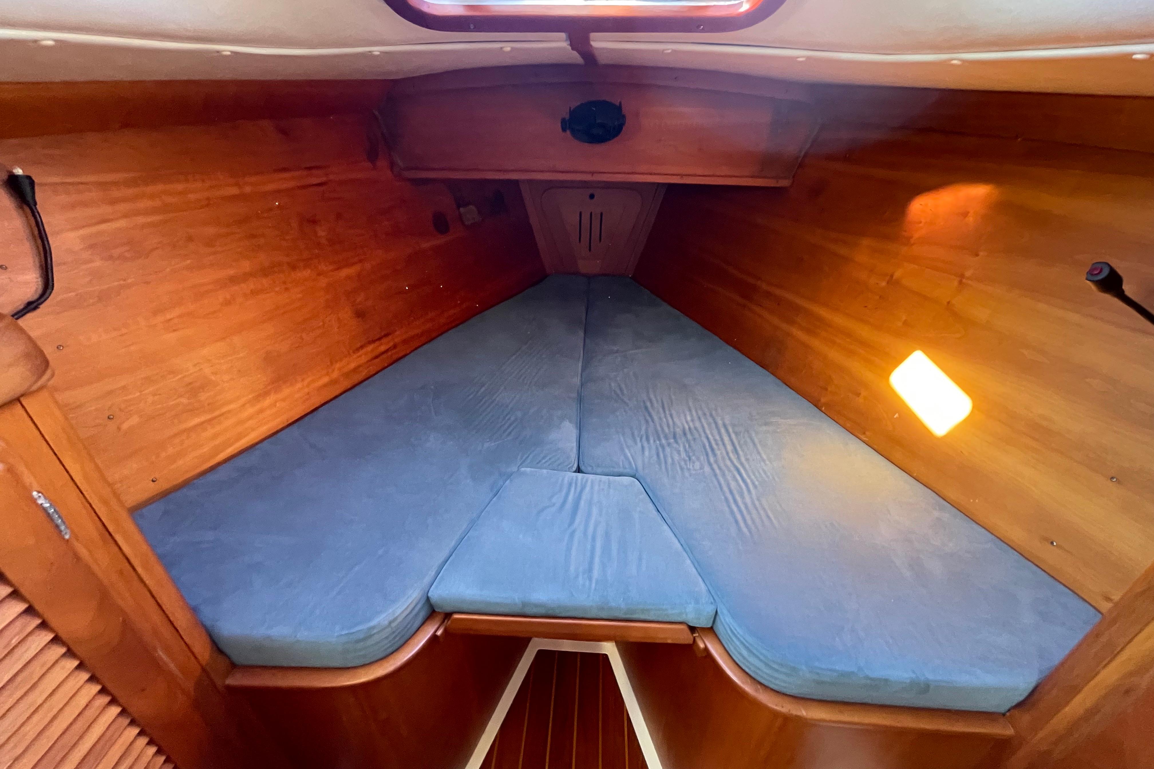 Cozy cabin interior of 1995 Freedom 35 sailboat with wooden finish and blue cushions.