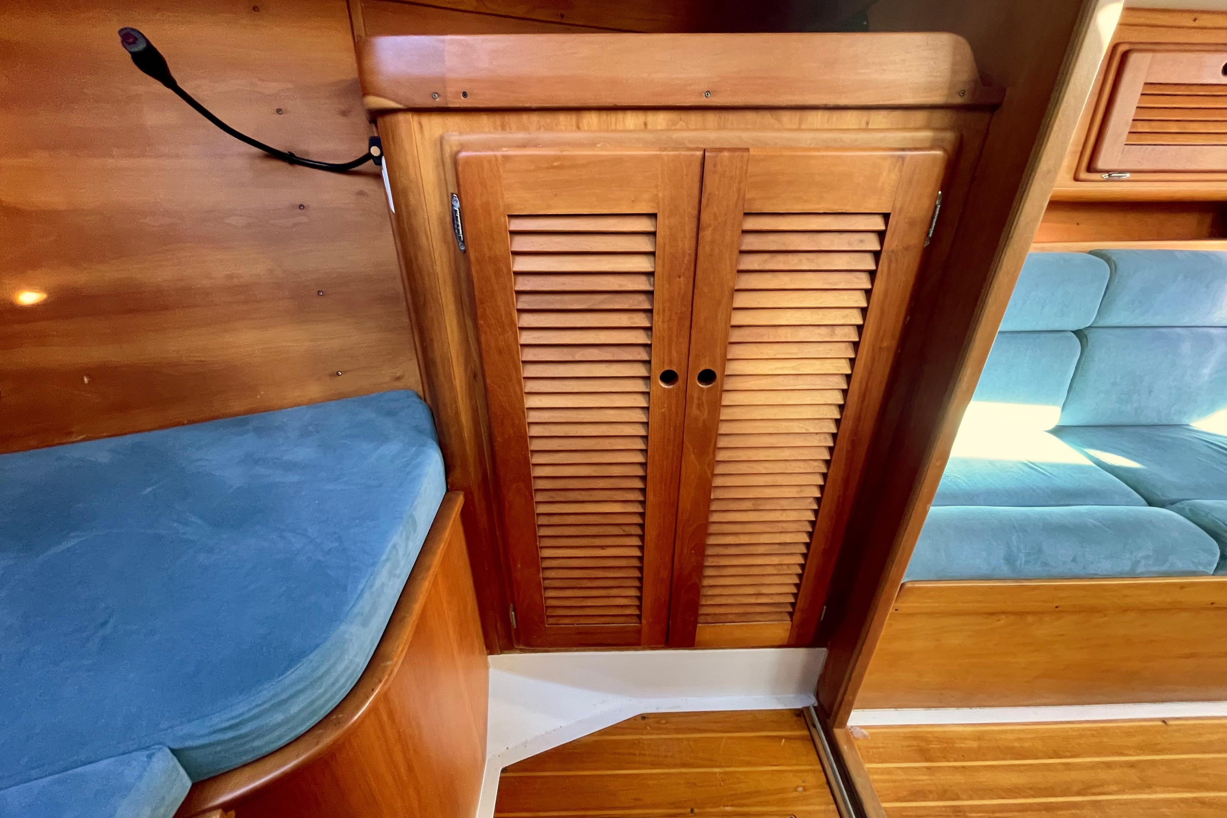Wooden interior of a 1995 Freedom 35 sailboat with blue cushions and louvered cabinet doors.