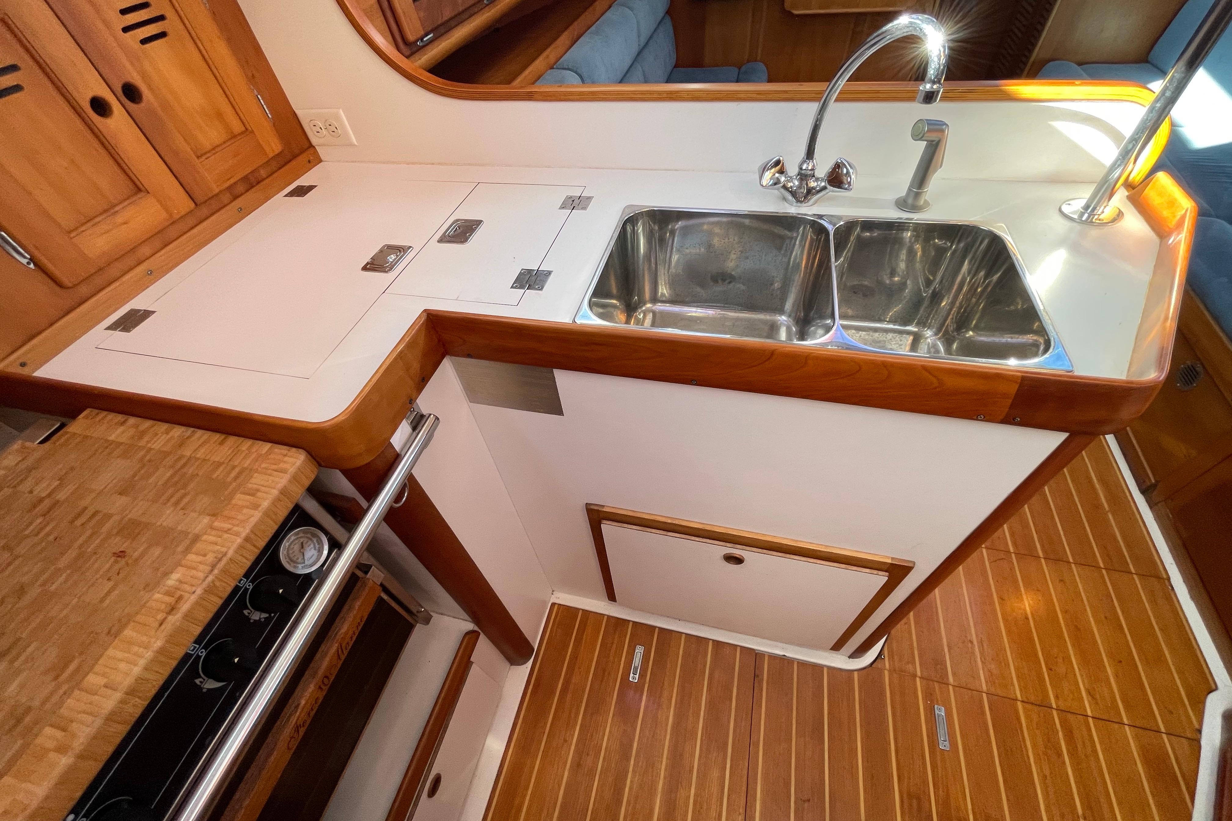 Galley kitchen in 1995 Freedom 35 sailboat with double sink and wooden cabinetry.