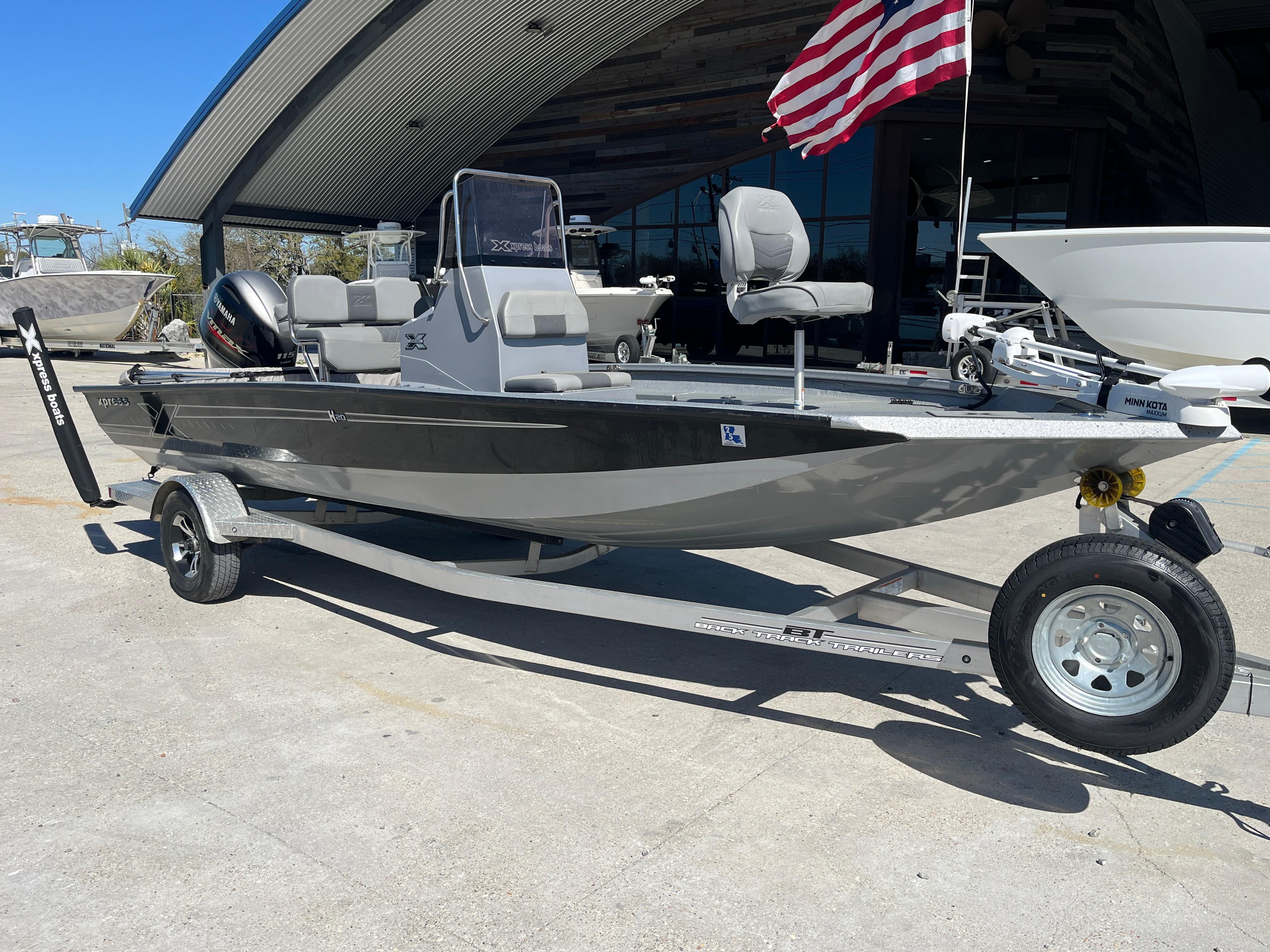 2022 Xpress H20B Bay Boat on trailer, parked outdoors with American flag in background.