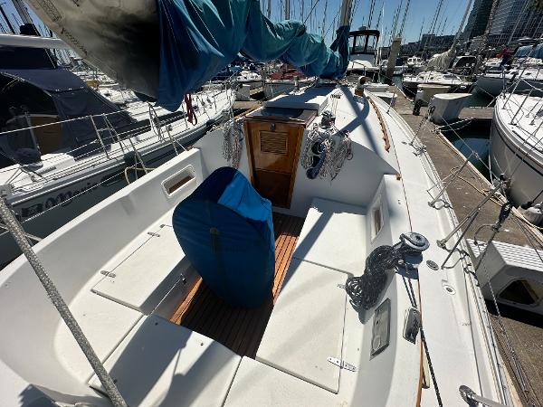 1986 Nonsuch Ultra sailboat cockpit in marina, featuring covered equipment and wooden accents.
