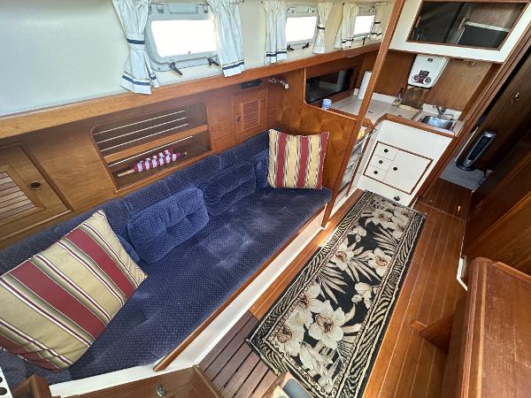 Cozy 1986 Nonsuch Ultra yacht interior with blue sofa, striped cushions, and floral rug.