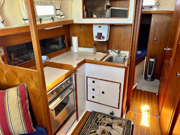 Compact kitchen in a 1986 Nonsuch Ultra sailboat with wood cabinetry and stainless steel appliances.