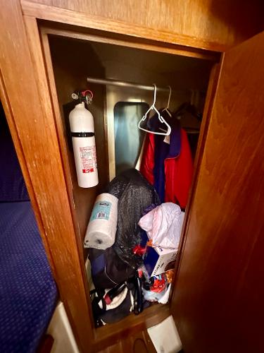 1986 Nonsuch Ultra closet with fire extinguisher, clothes, and miscellaneous items.