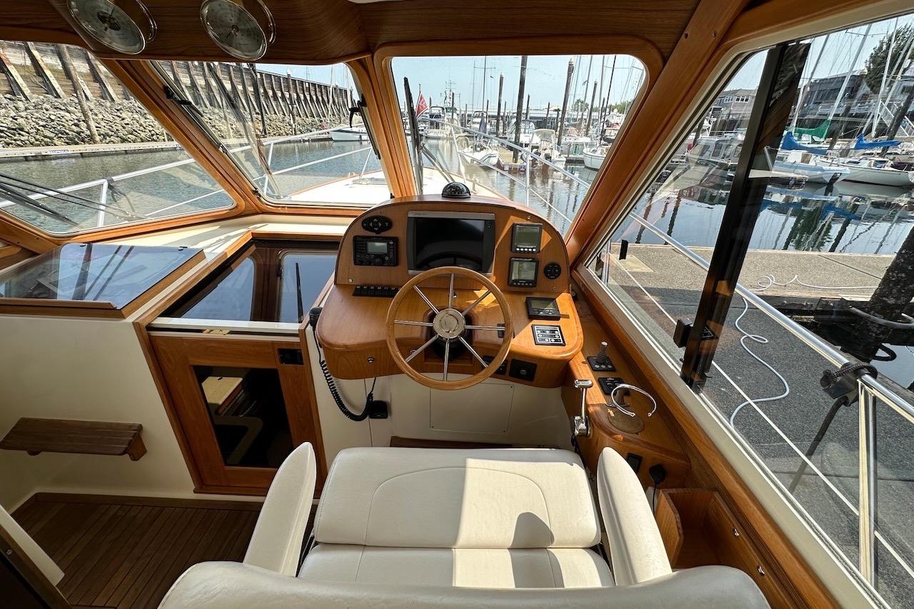 2007 Legacy Yachts 32 helm with wooden steering wheel and marina view.