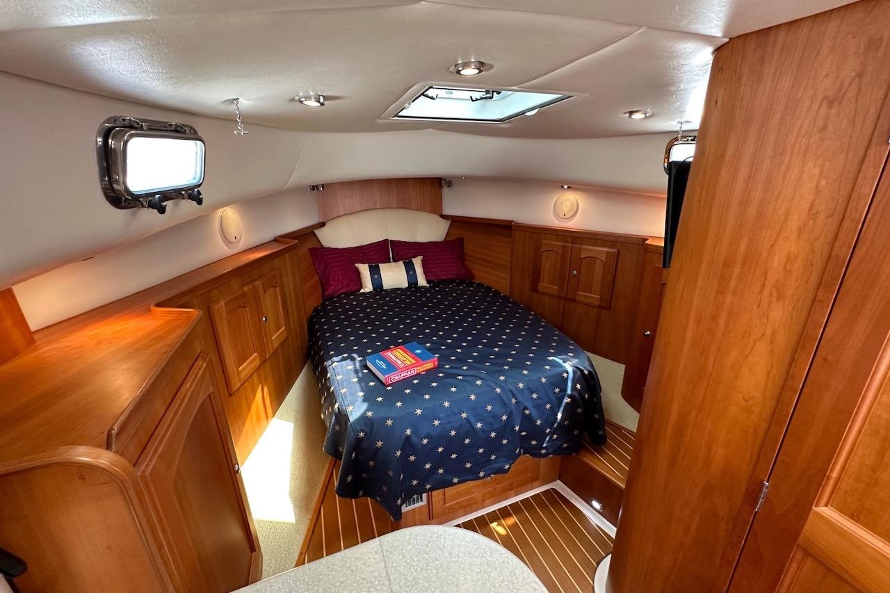 Luxurious 2007 Legacy Yachts 32 cabin interior with cozy bed and wooden cabinetry.