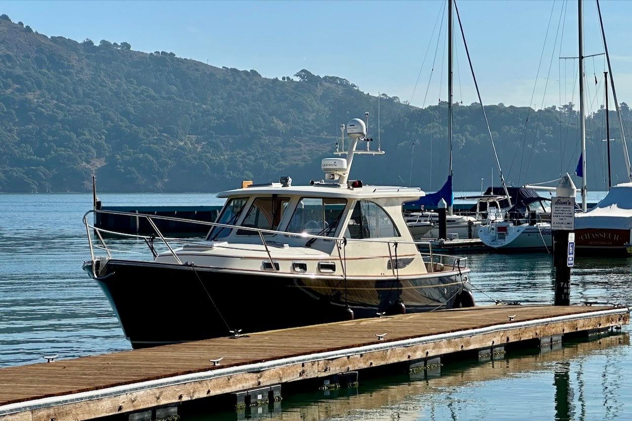 2007 Legacy Yachts 32 docked at a marina with scenic hillside backdrop.