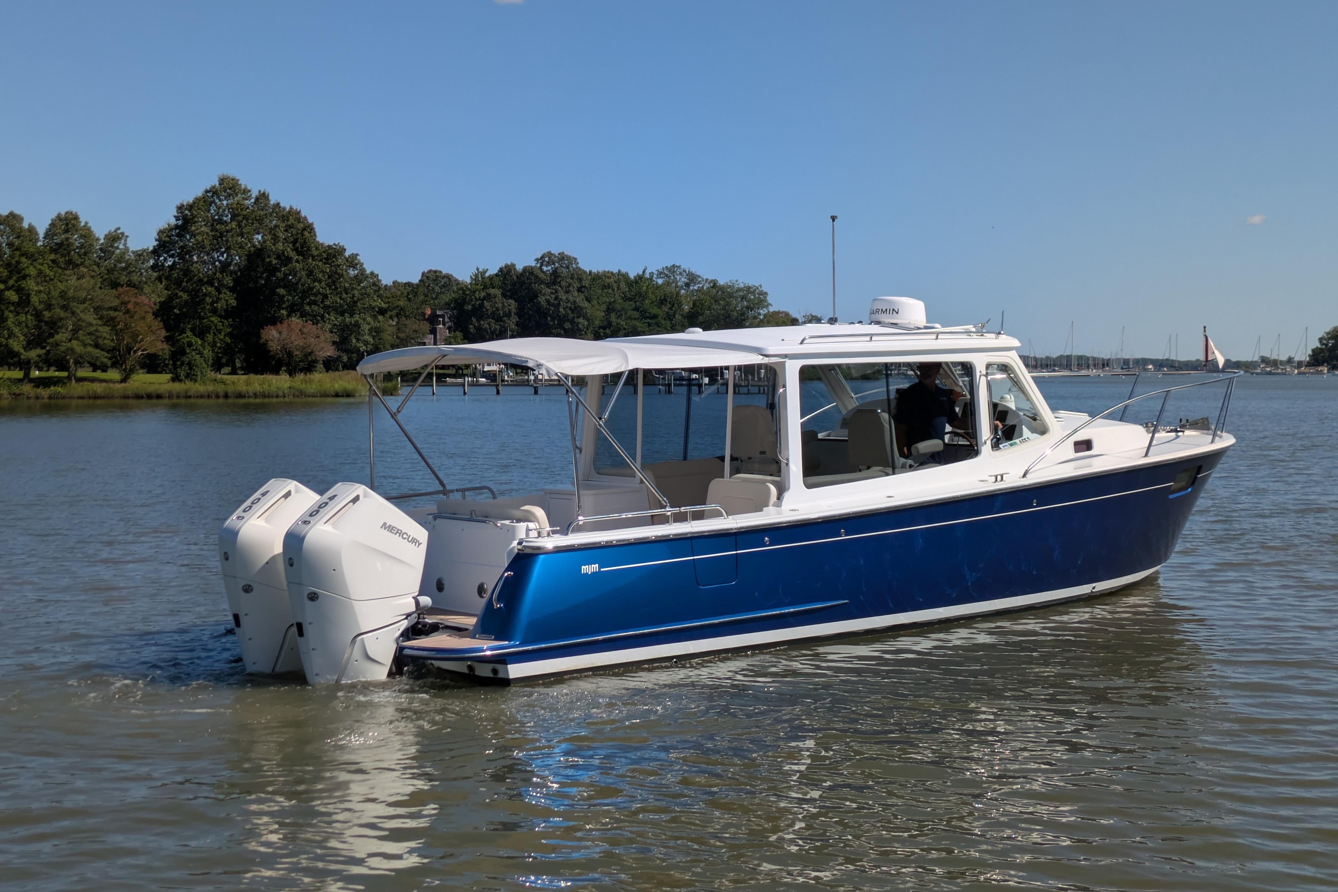 2024 MJM 35 boat with dual Mercury engines on a calm lake.