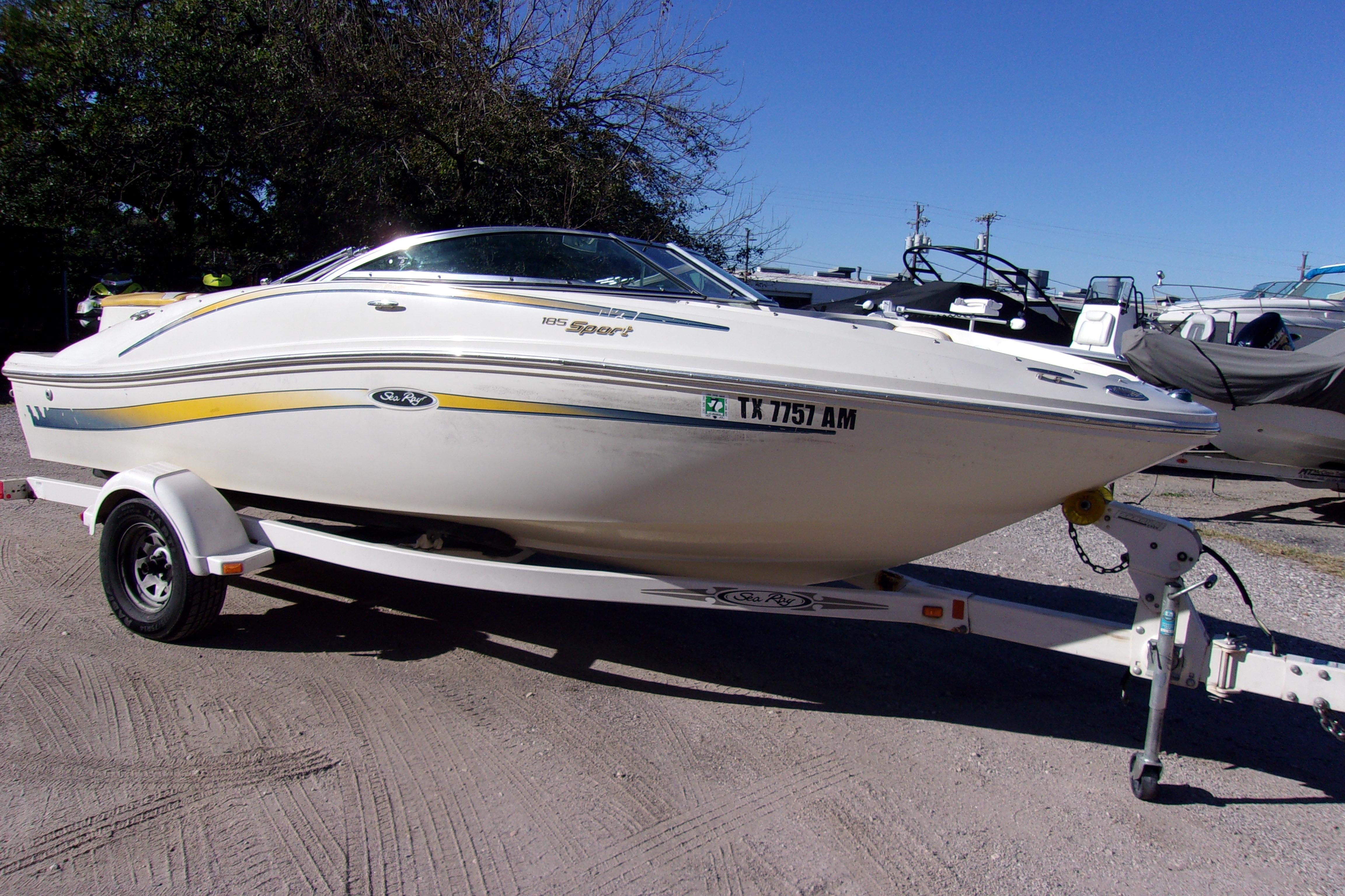 2007 Sea Ray 185 Sport boat on trailer, parked outdoors under clear blue sky.