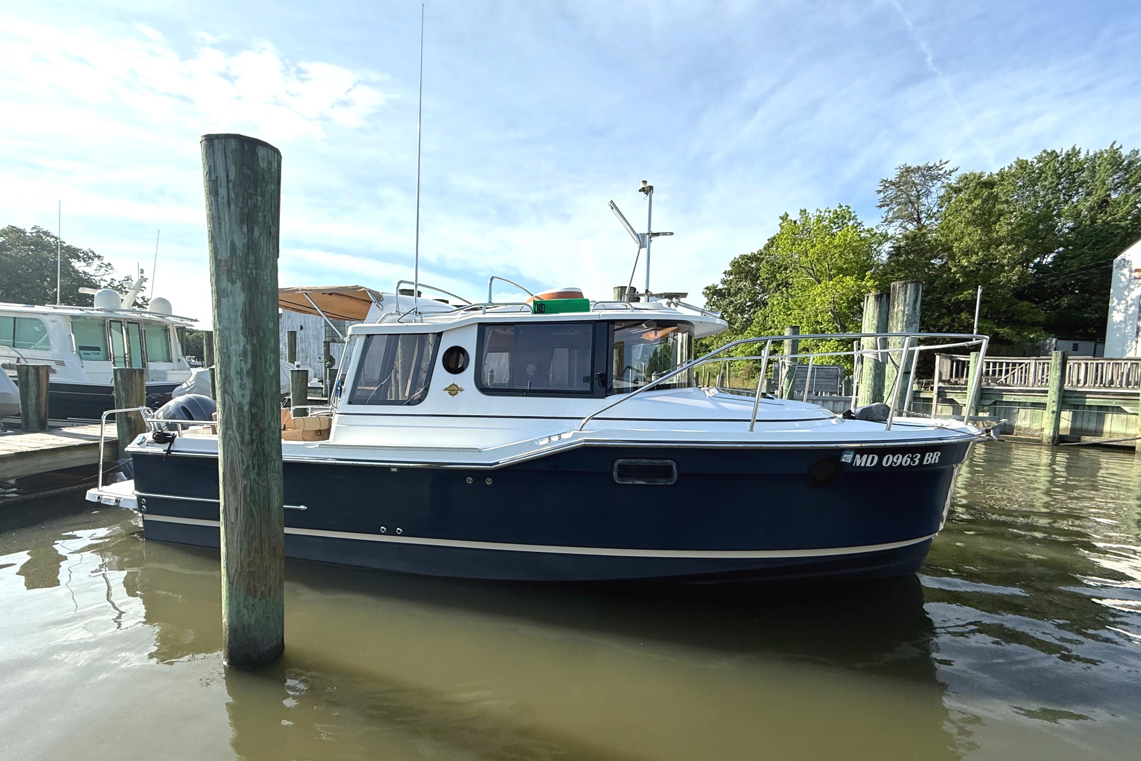 2020 Ranger Tugs R-23 boat docked in a marina, surrounded by calm water.