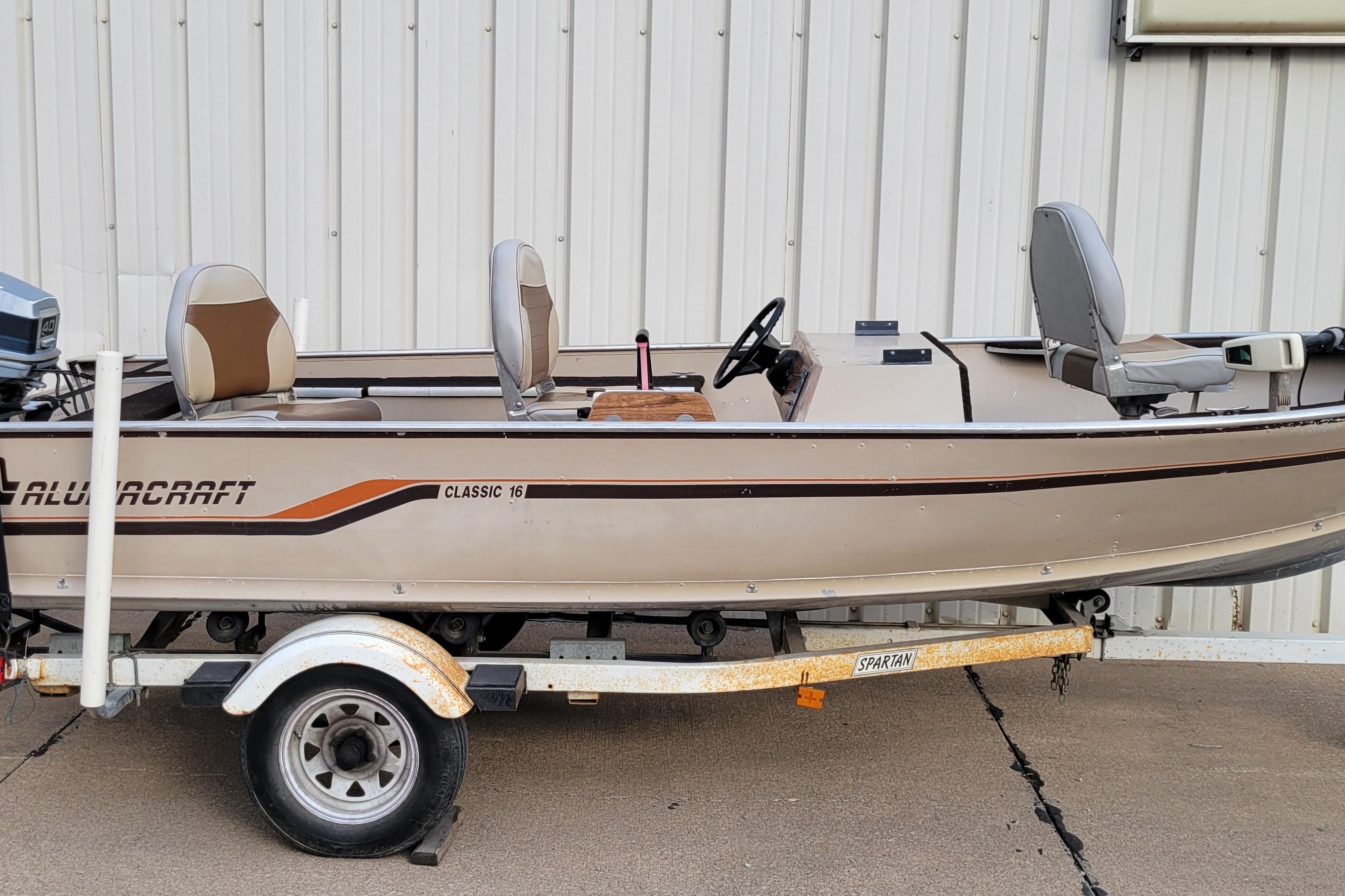 1987 Alumacraft Classic 165 CS boat on trailer, beige with brown accents, parked outdoors.