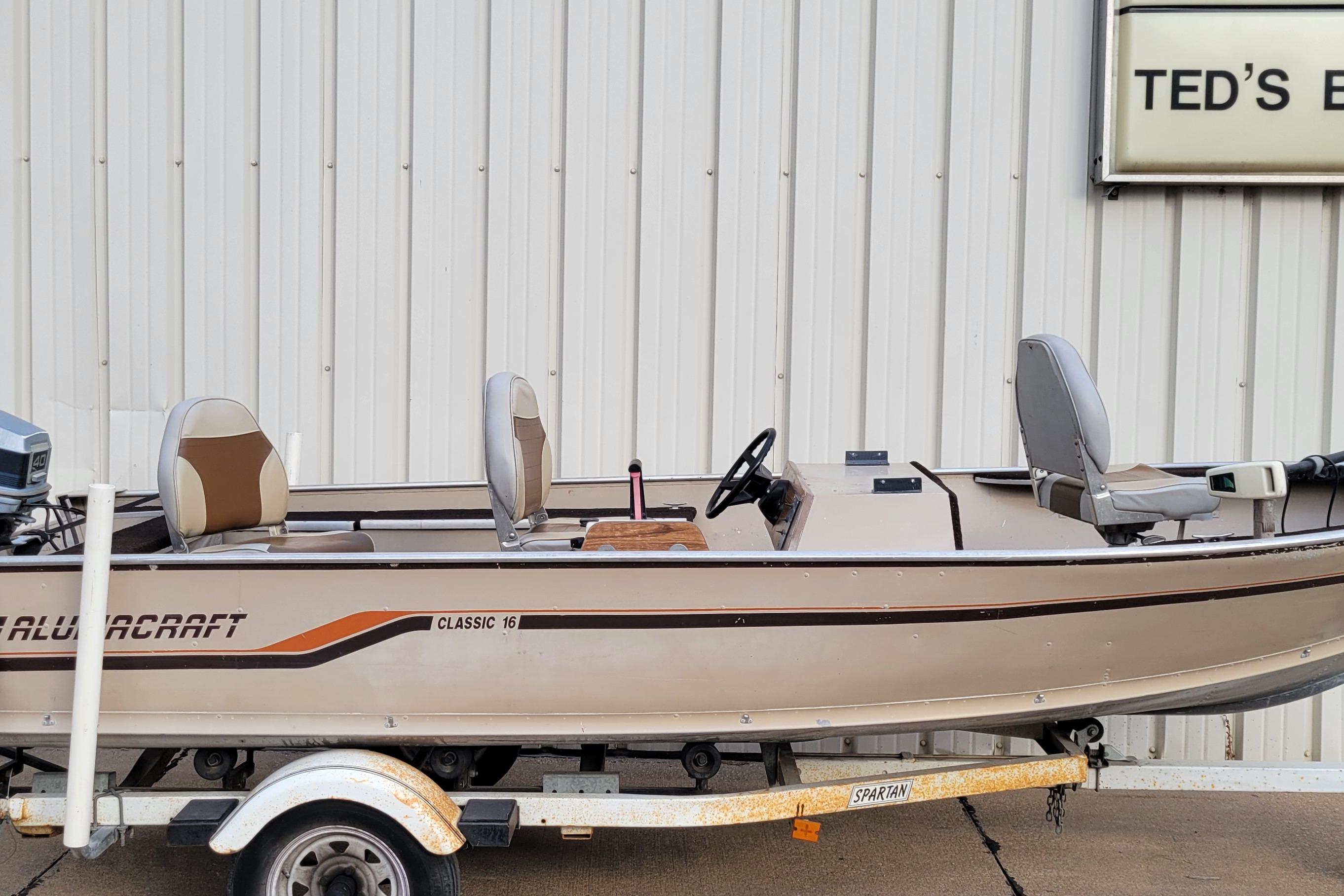 1987 Alumacraft Classic 165 CS boat on trailer, parked outside a building.