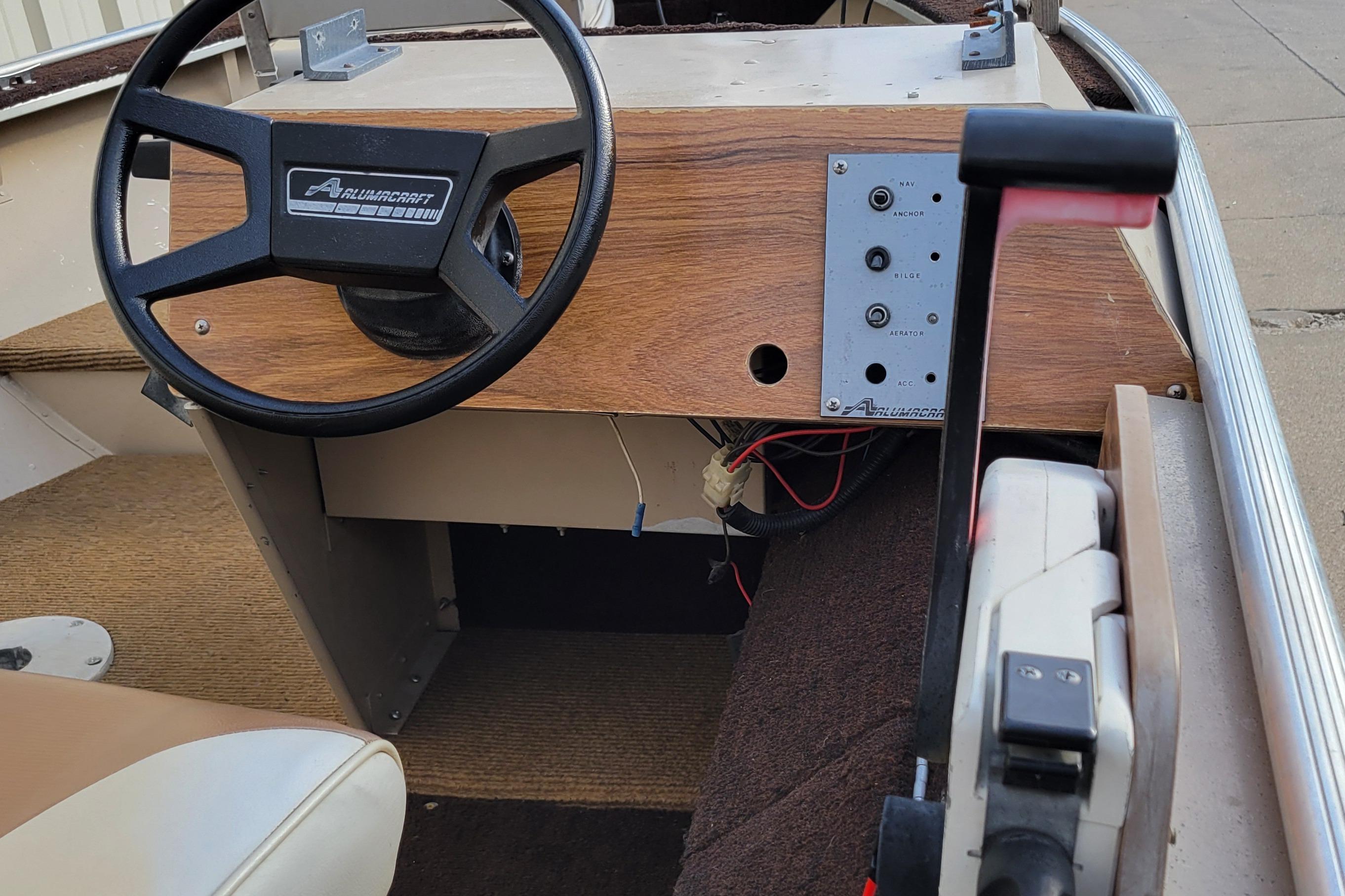 1987 Alumacraft Classic 165 CS boat dashboard with steering wheel and control panel.