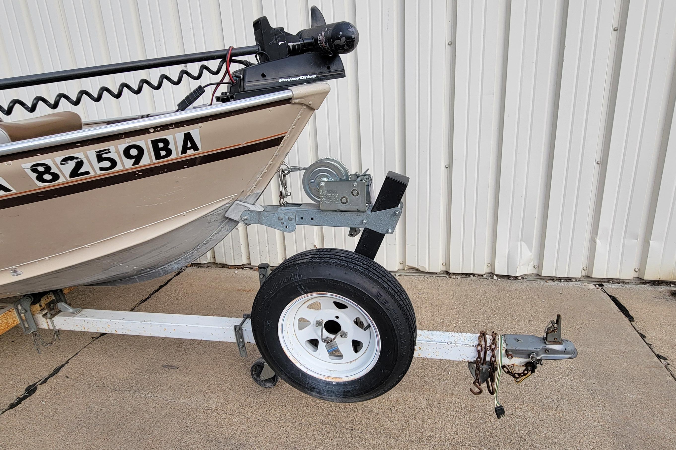 1987 Alumacraft Classic 165 CS boat on trailer, parked by a corrugated metal wall.