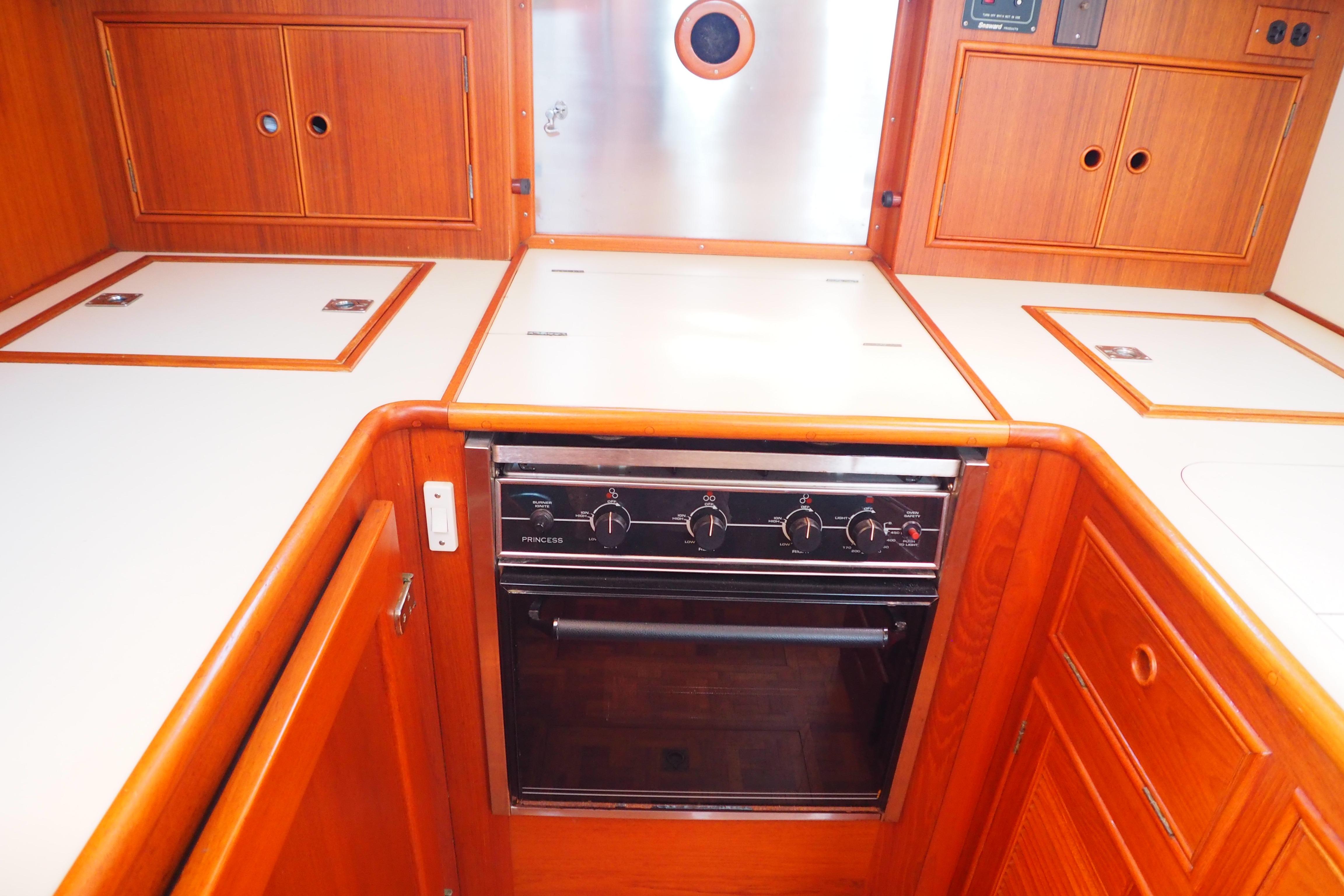 Galley kitchen in 1995 Grand Banks 38 Eastbay EX yacht with wood cabinetry and stove.