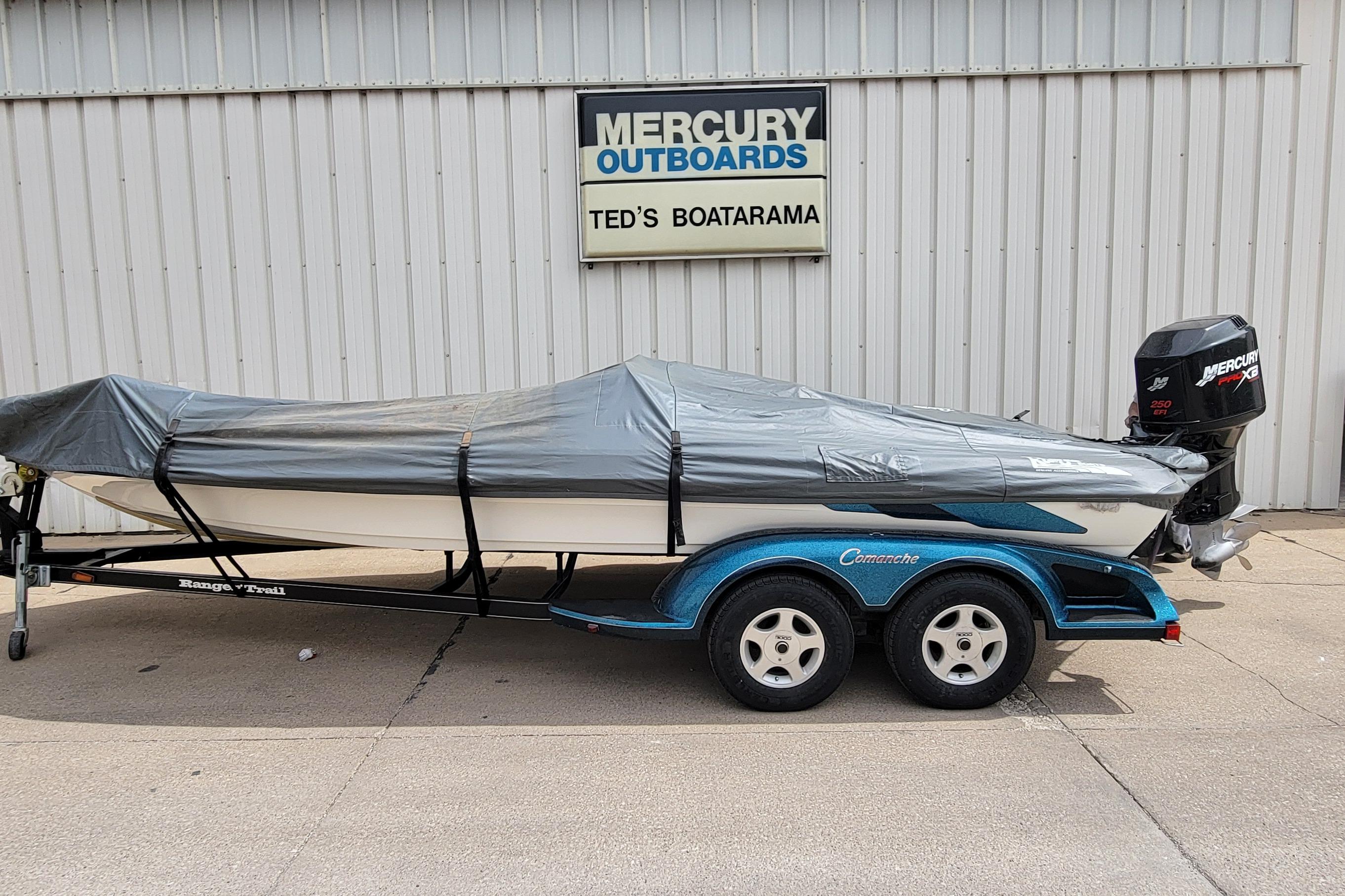 Covered 2000 Ranger 522DVX Comanche boat on trailer, parked outside Ted's Boatarama.