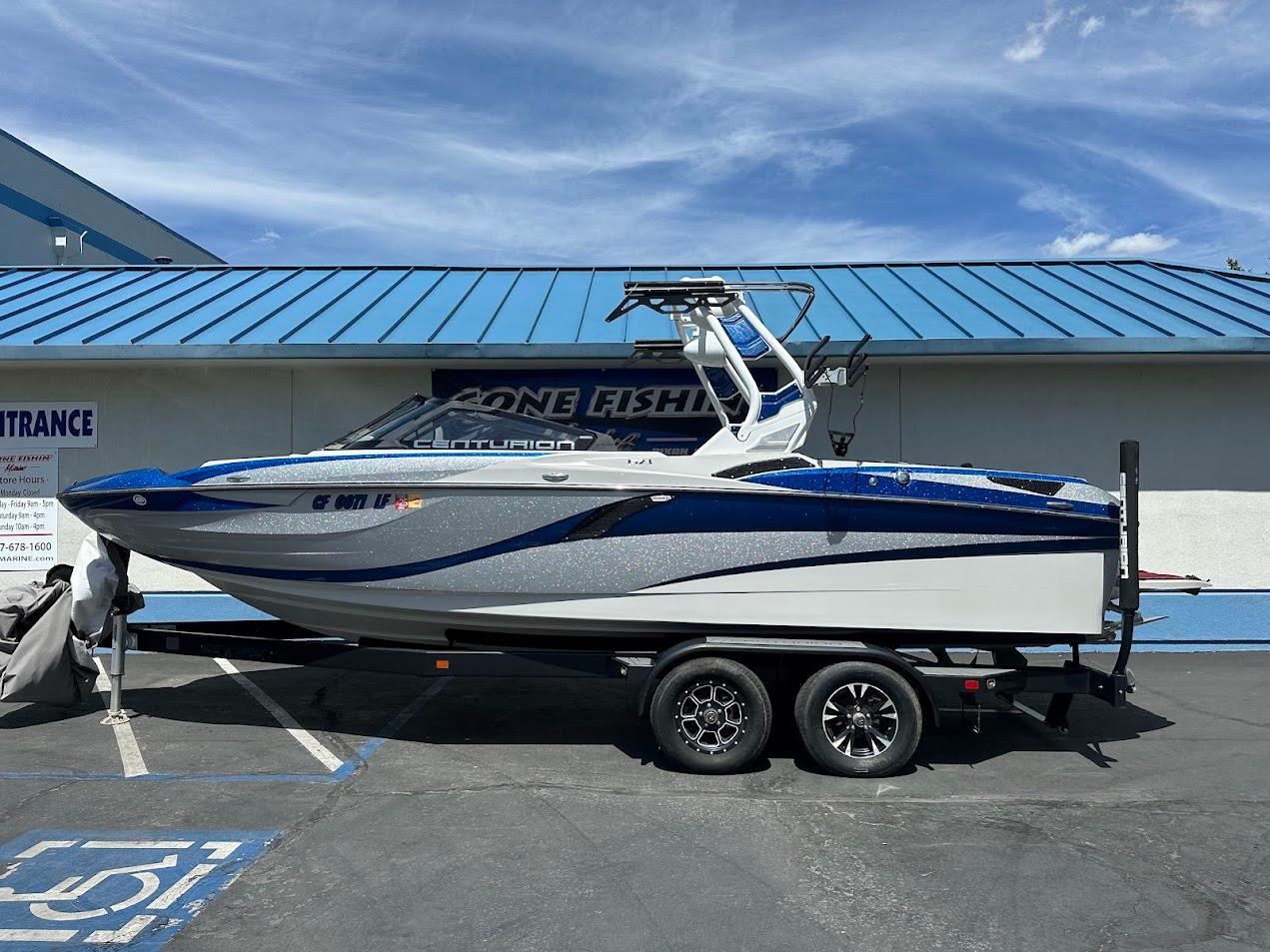 2021 Centurion Fi23 boat on trailer, blue and white design, parked outside a building.