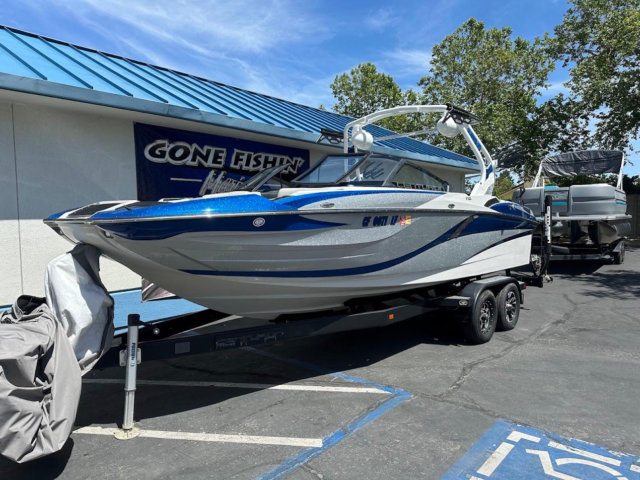 2021 Centurion Fi23 boat on trailer at dealership, blue and white design, sunny day.