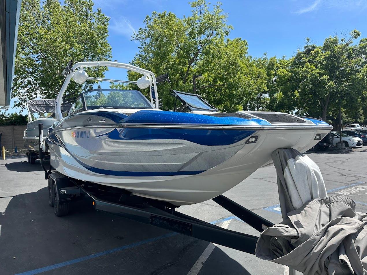 2021 Centurion Fi23 boat on trailer, parked outdoors under clear sky.