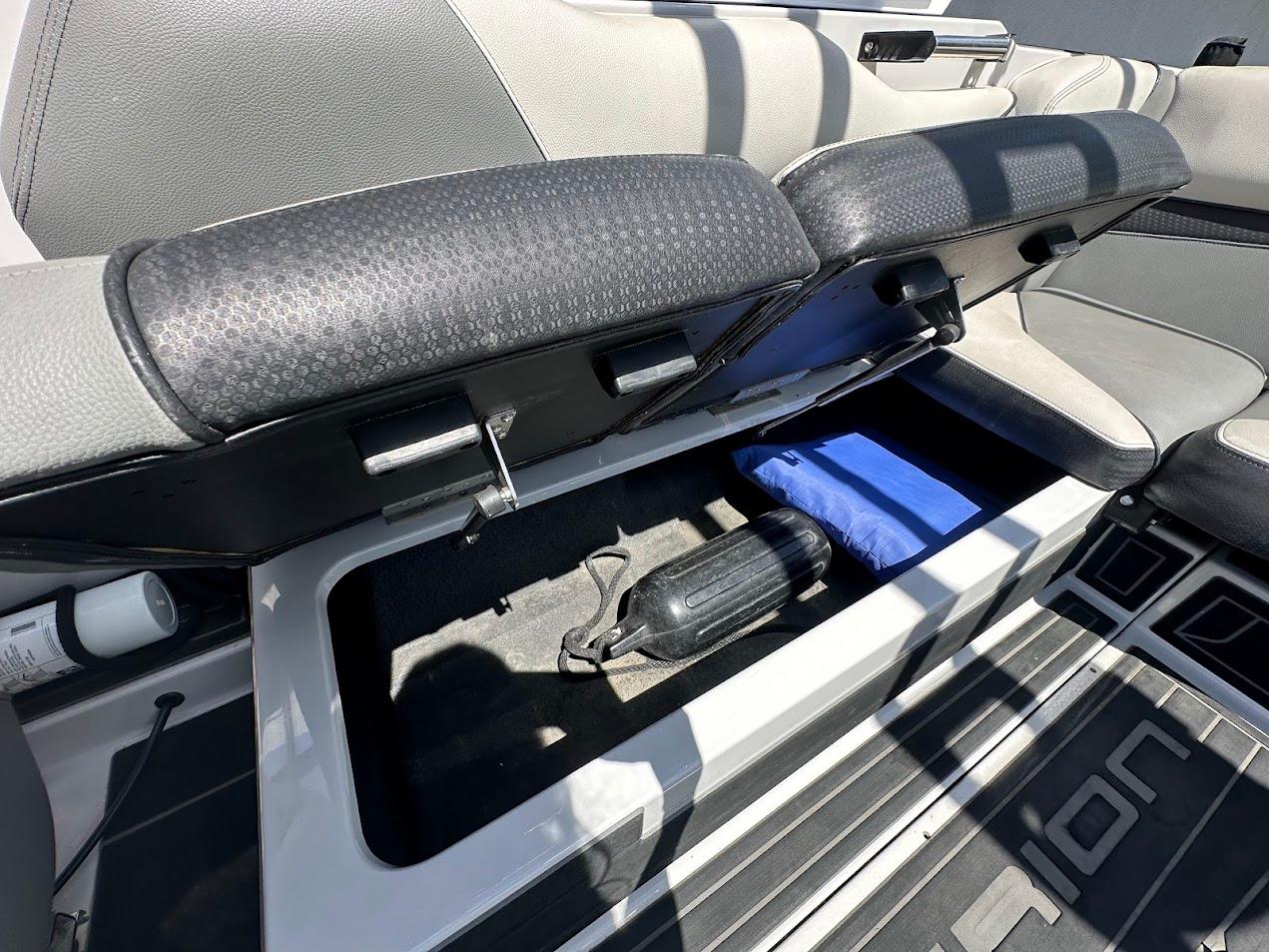 2021 Centurion Fi23 boat storage compartment with open seat, revealing interior space and accessories.