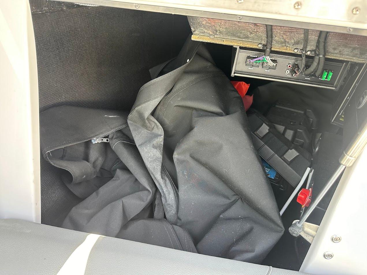 Interior storage compartment of a 2021 Centurion Fi23 boat with equipment and cables.