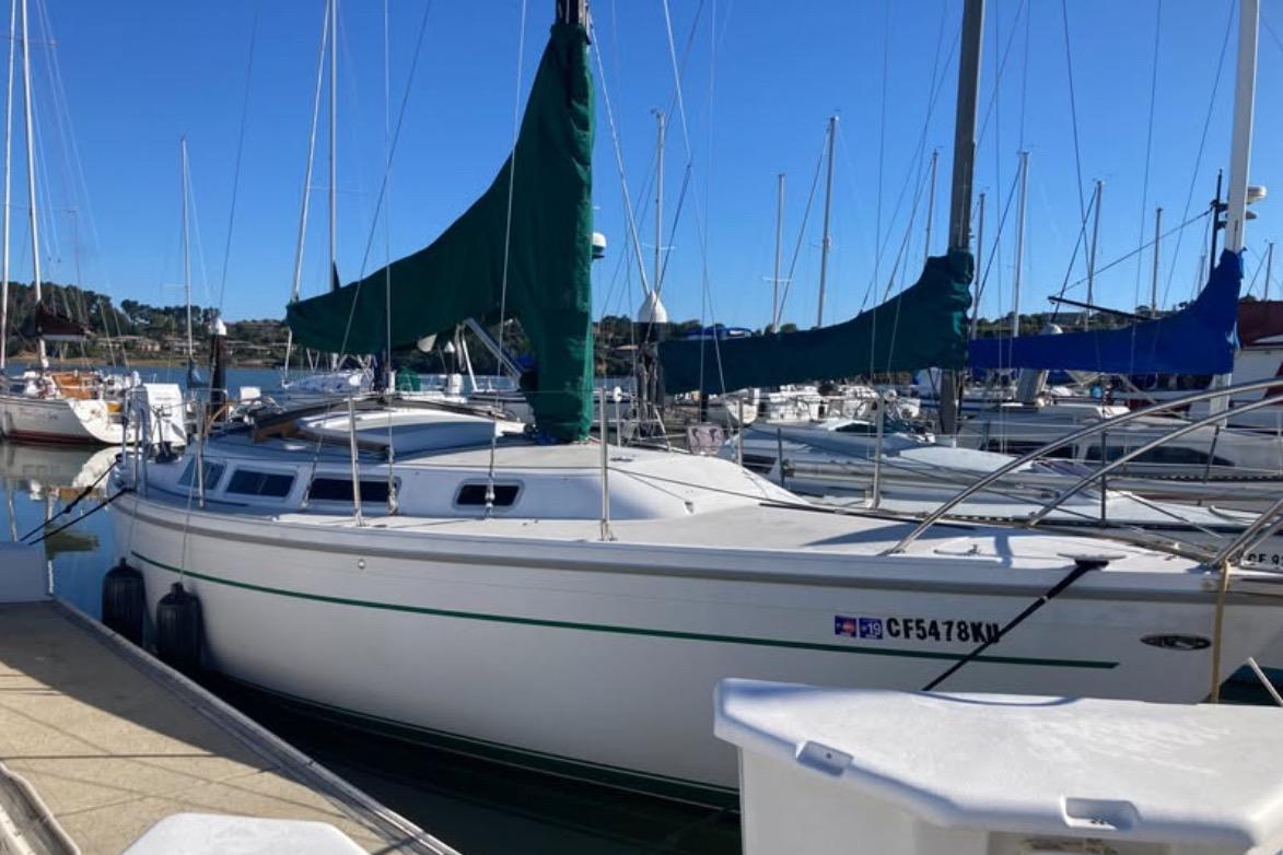 1981 Catalina 30 sailboat docked in a marina under clear blue skies.
