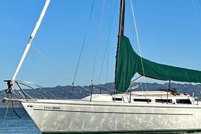 1981 Catalina 30 sailboat with green sail cover on calm water.