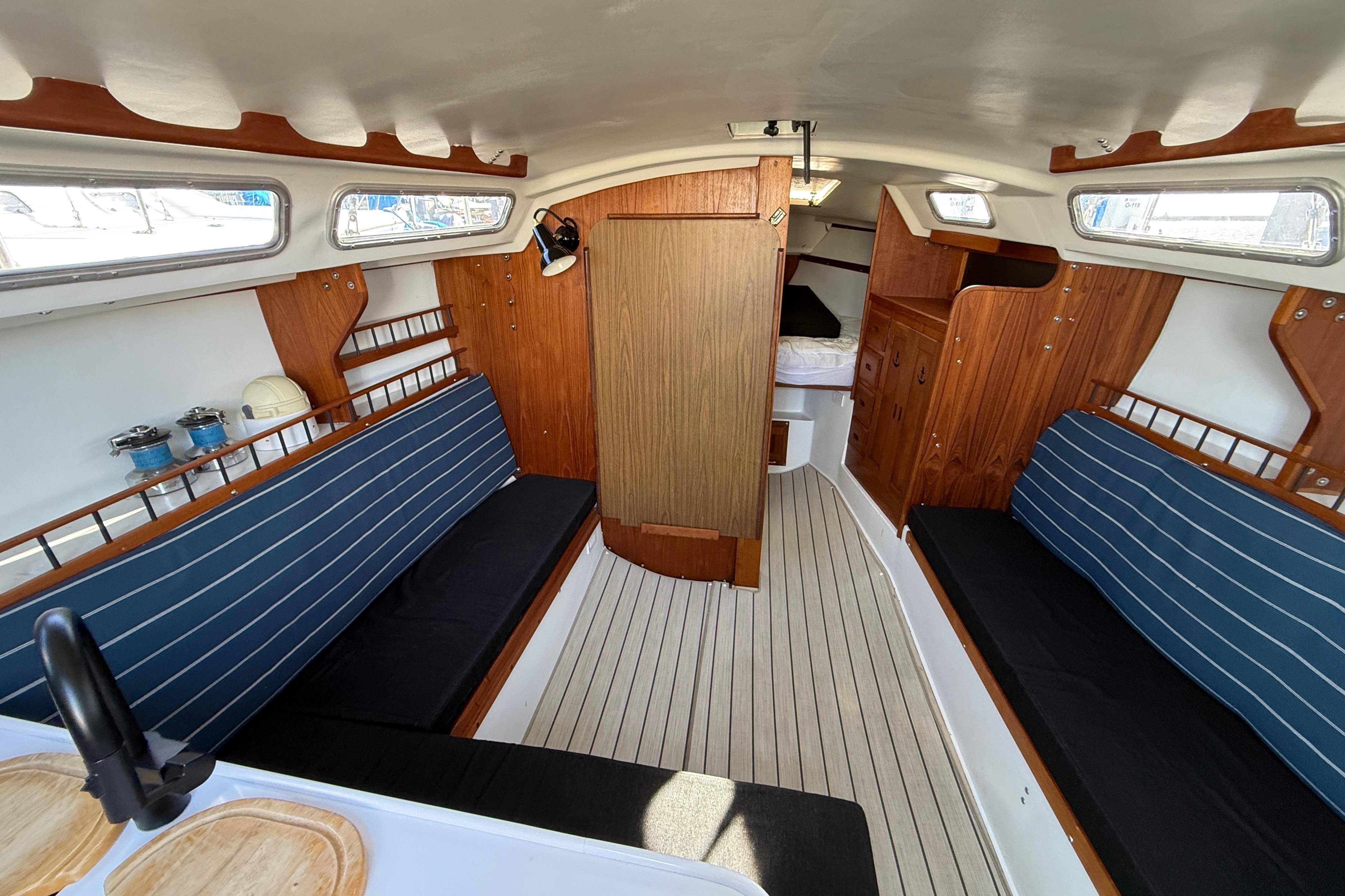Interior of 1981 Catalina 30 sailboat with wooden accents and blue-striped seating.