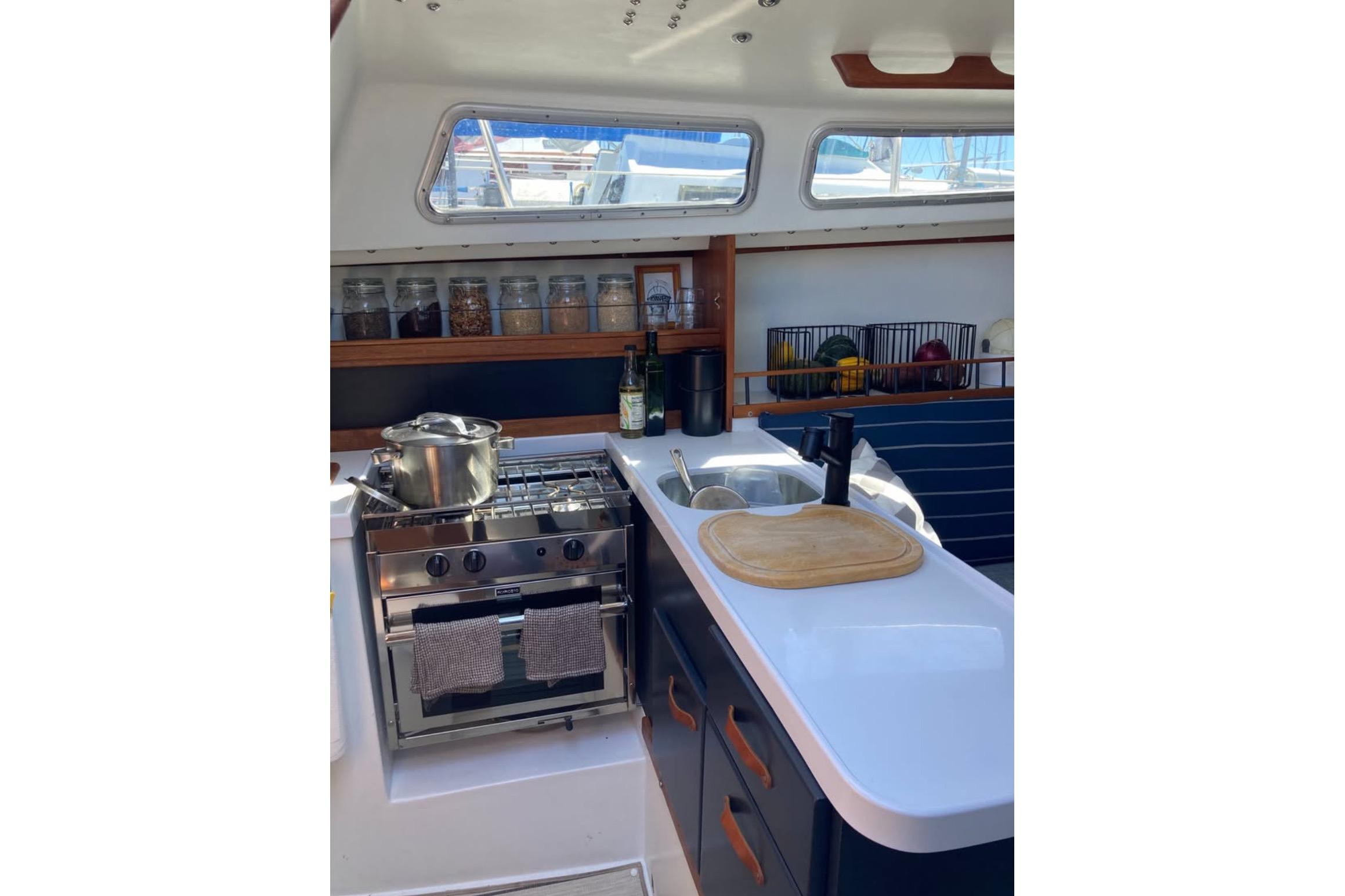 1981 Catalina 30 yacht kitchen with stove, sink, and storage jars.