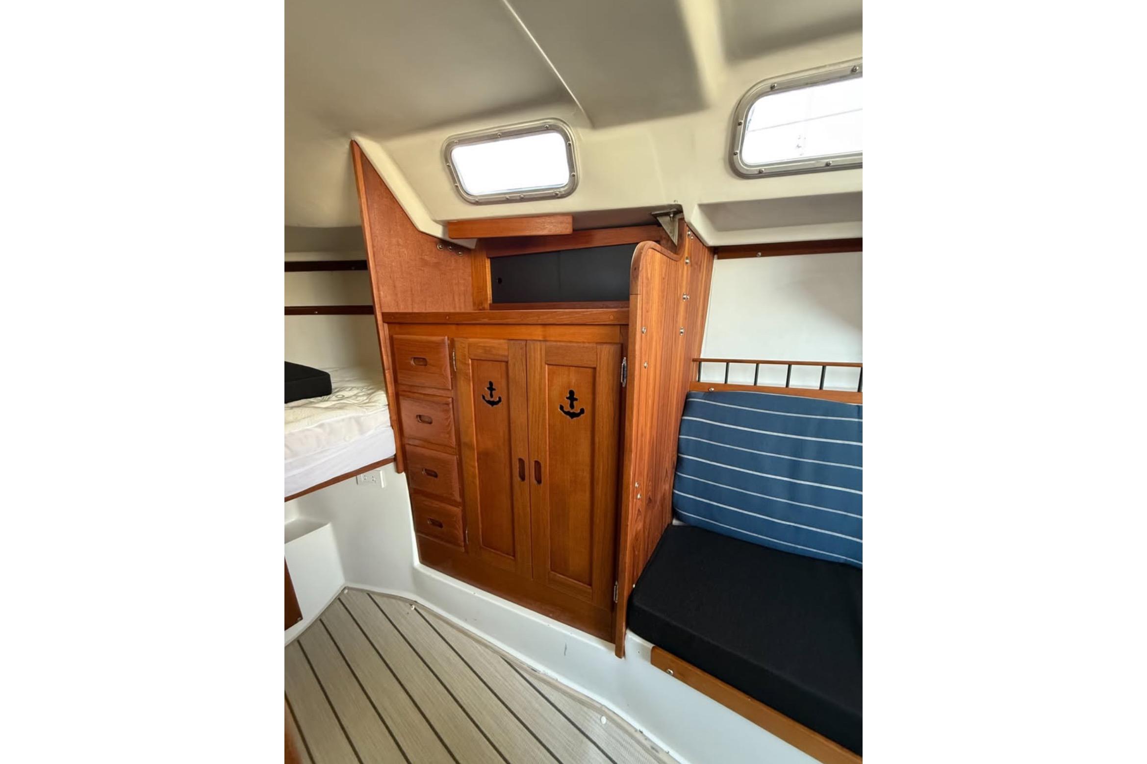 Interior of 1981 Catalina 30 sailboat with wooden cabinetry and striped seating.