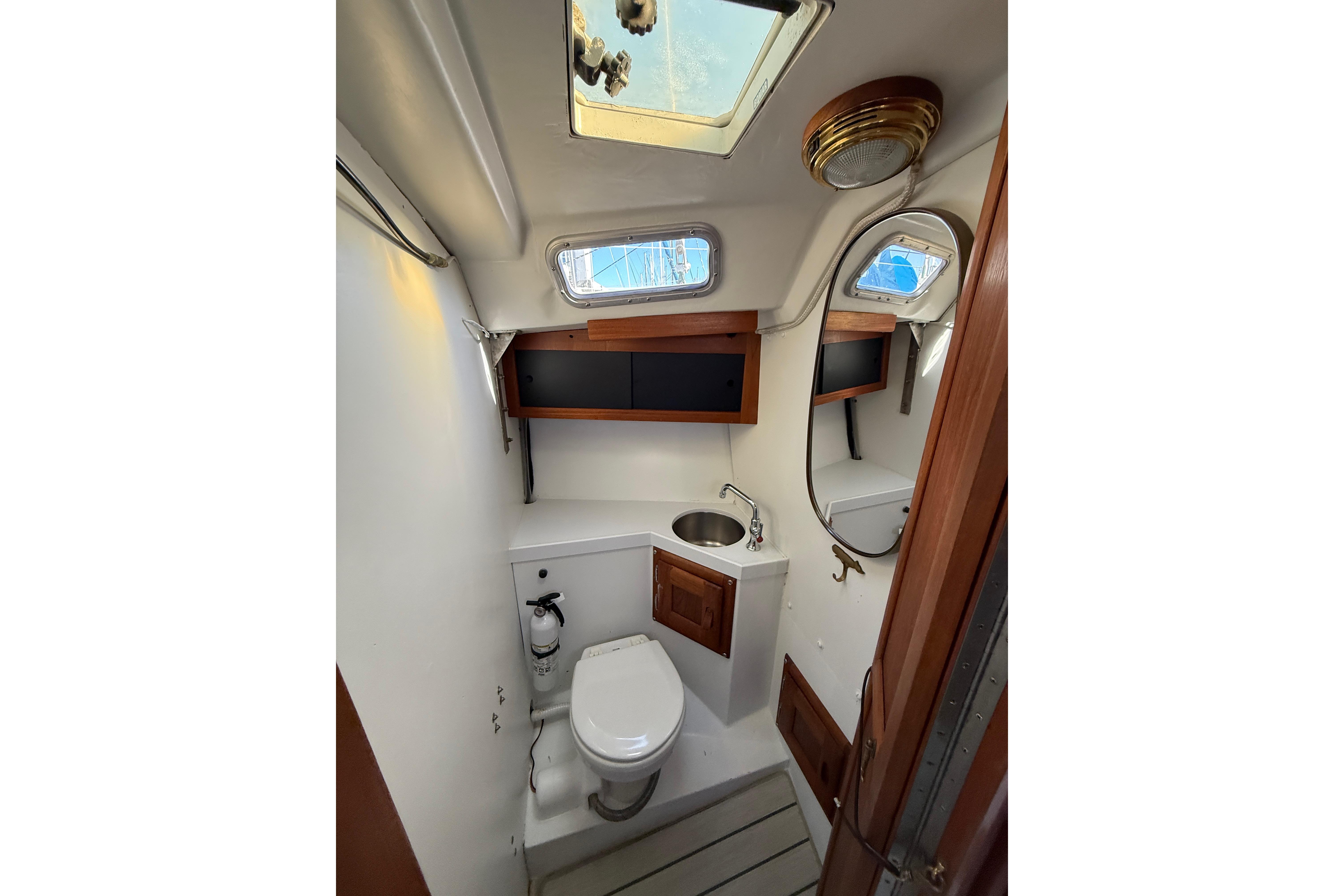 1981 Catalina 30 sailboat bathroom with toilet, sink, and wooden cabinets.