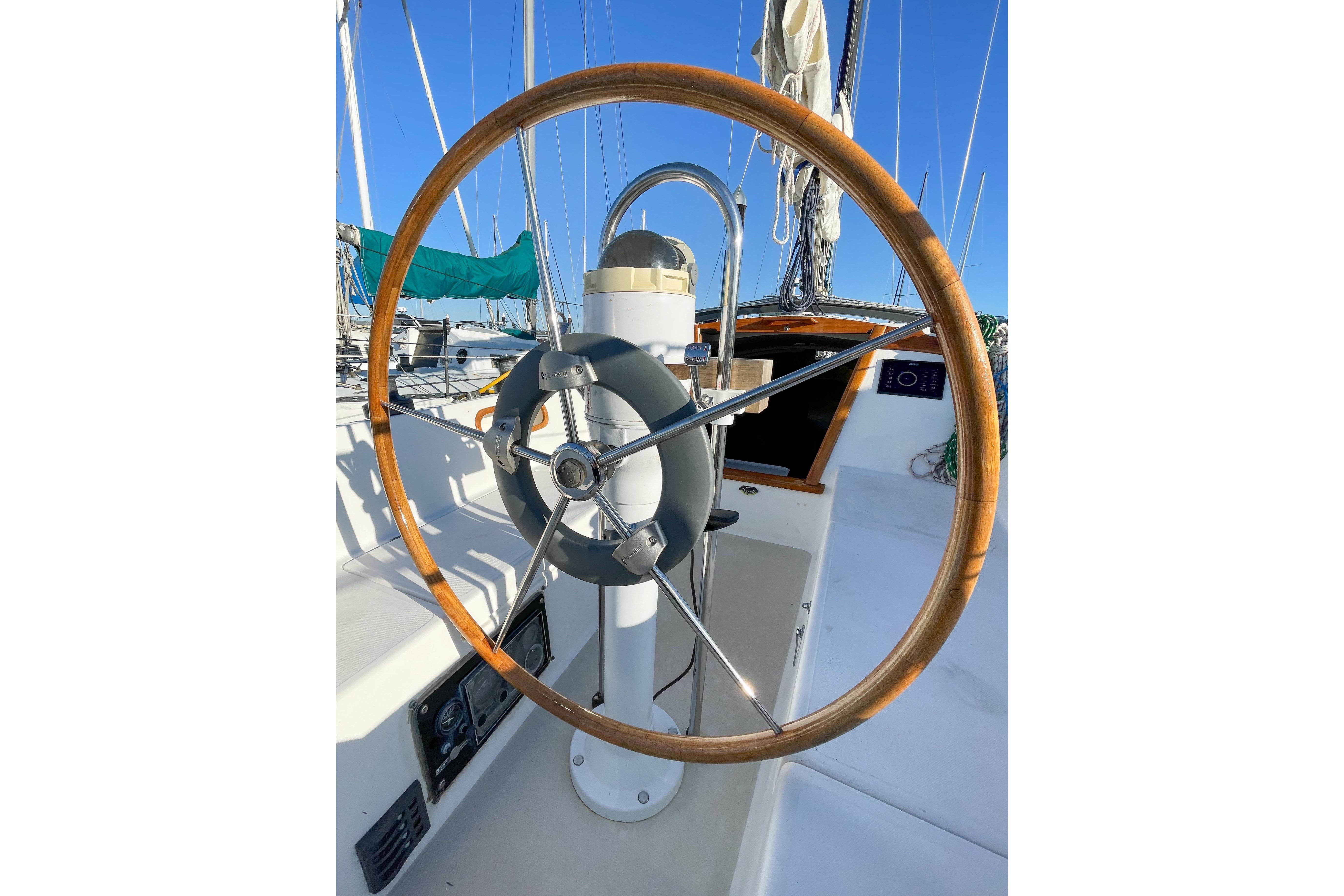 1981 Catalina 30 sailboat helm with wooden wheel and clear blue sky.