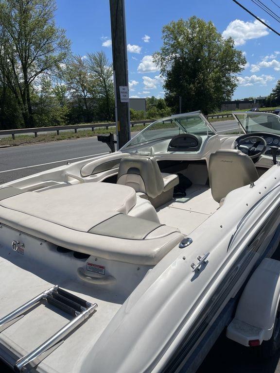 2004 Sea Ray 185 Sport boat with beige interior, parked near a road under a clear sky.
