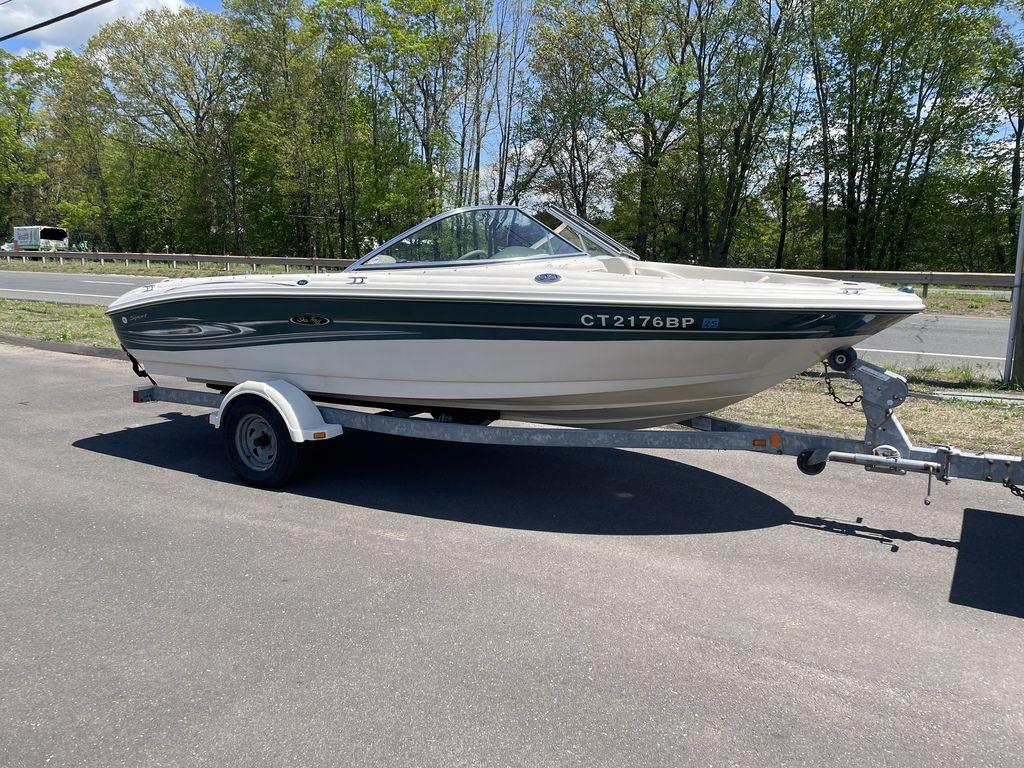 2004 Sea Ray 185 Sport boat on trailer, parked on road with trees in background.