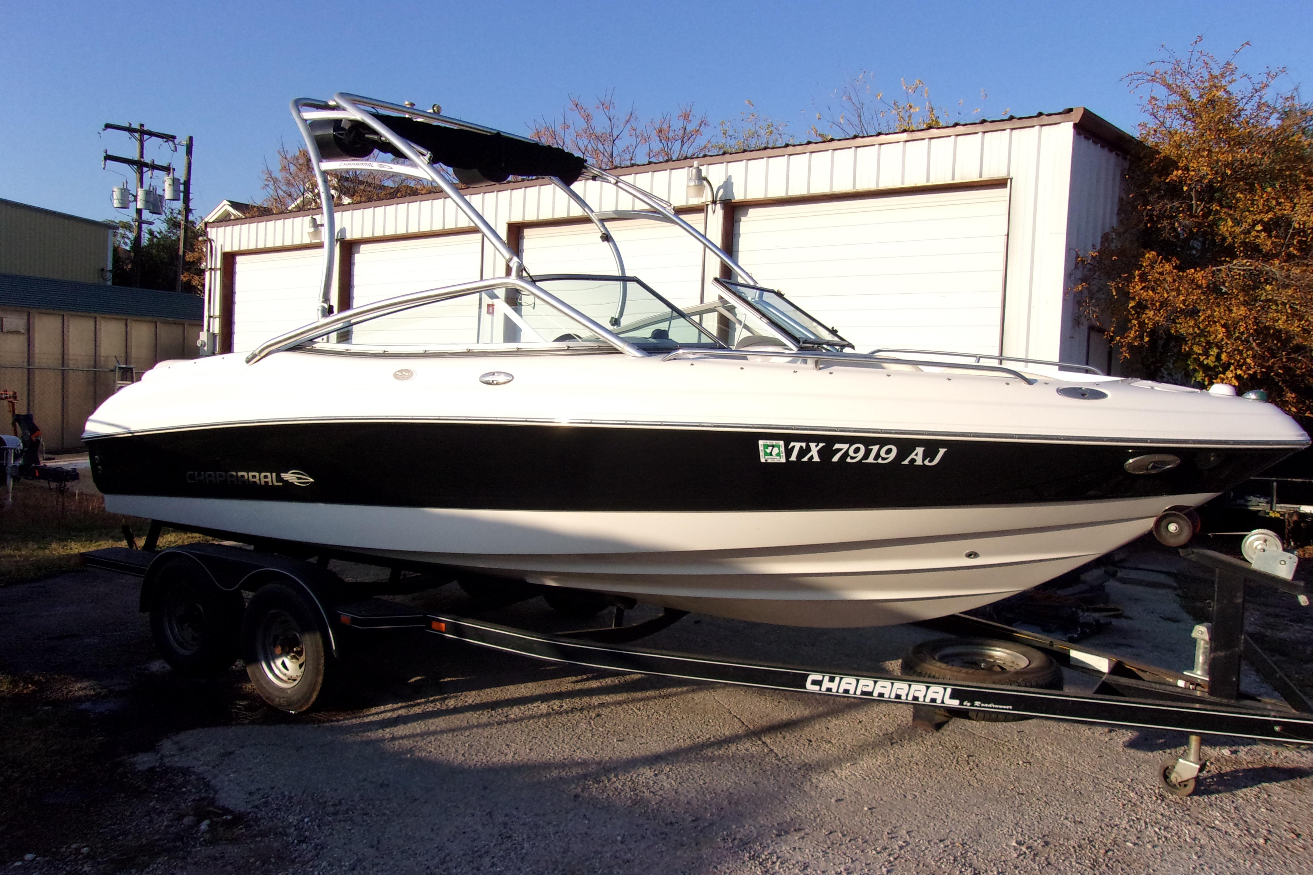 2007 Chaparral 210 SSi boat on trailer, parked outdoors near storage buildings.