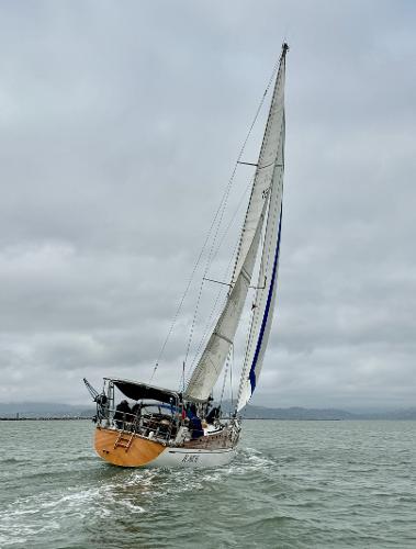 1983 Tayana 52 Aft Cockpit sailboat navigating on a cloudy day.