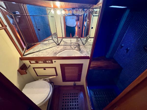Bathroom interior of 1983 Tayana 52 Aft Cockpit yacht with mirrored cabinets and wooden accents.