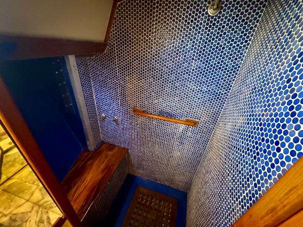 Shower area in 1983 Tayana 52 Aft Cockpit yacht with blue mosaic tiles and wooden accents.