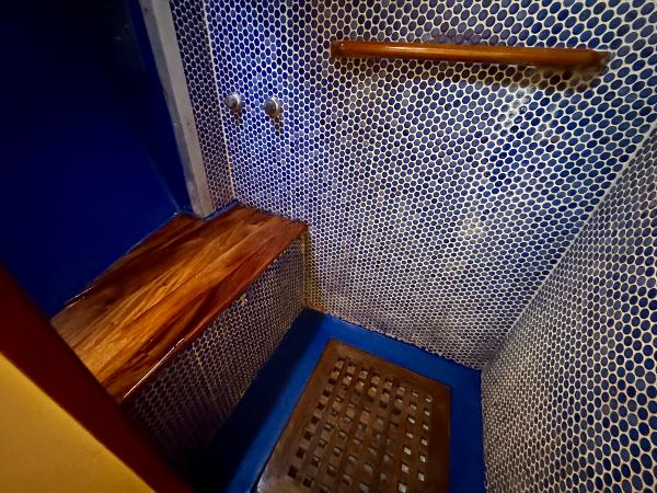 Shower area in 1983 Tayana 52 Aft Cockpit yacht with wooden bench and blue mosaic tiles.