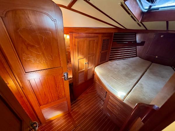 Cozy wooden cabin interior of 1983 Tayana 52 Aft Cockpit sailboat with bed and storage.