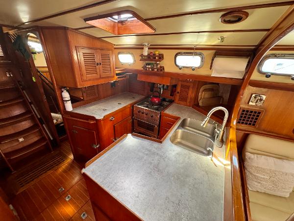 Interior of 1983 Tayana 52 Aft Cockpit yacht, featuring a wooden kitchen and dining area.
